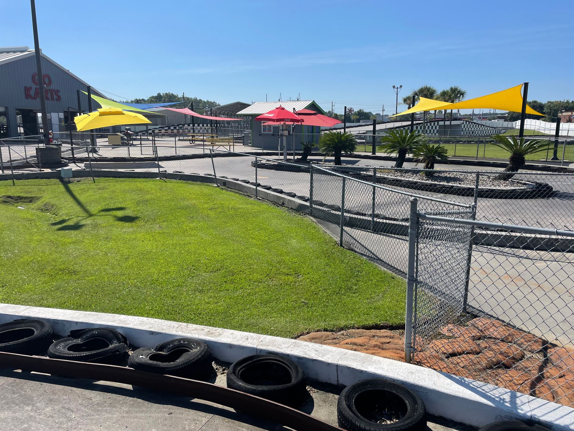 A go kart track is surrounded by a chain link fence and tires.