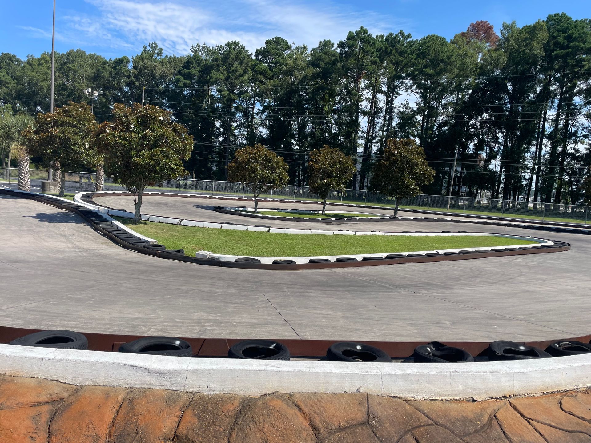 A go kart track with trees in the background on a sunny day.
