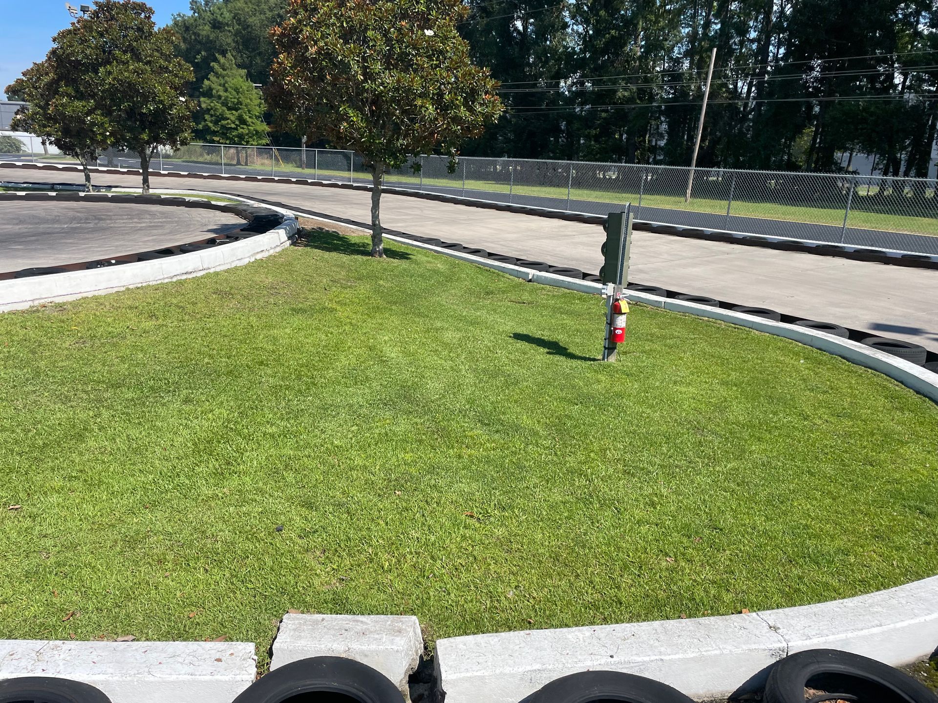 A race track with a fire extinguisher in the grass.
