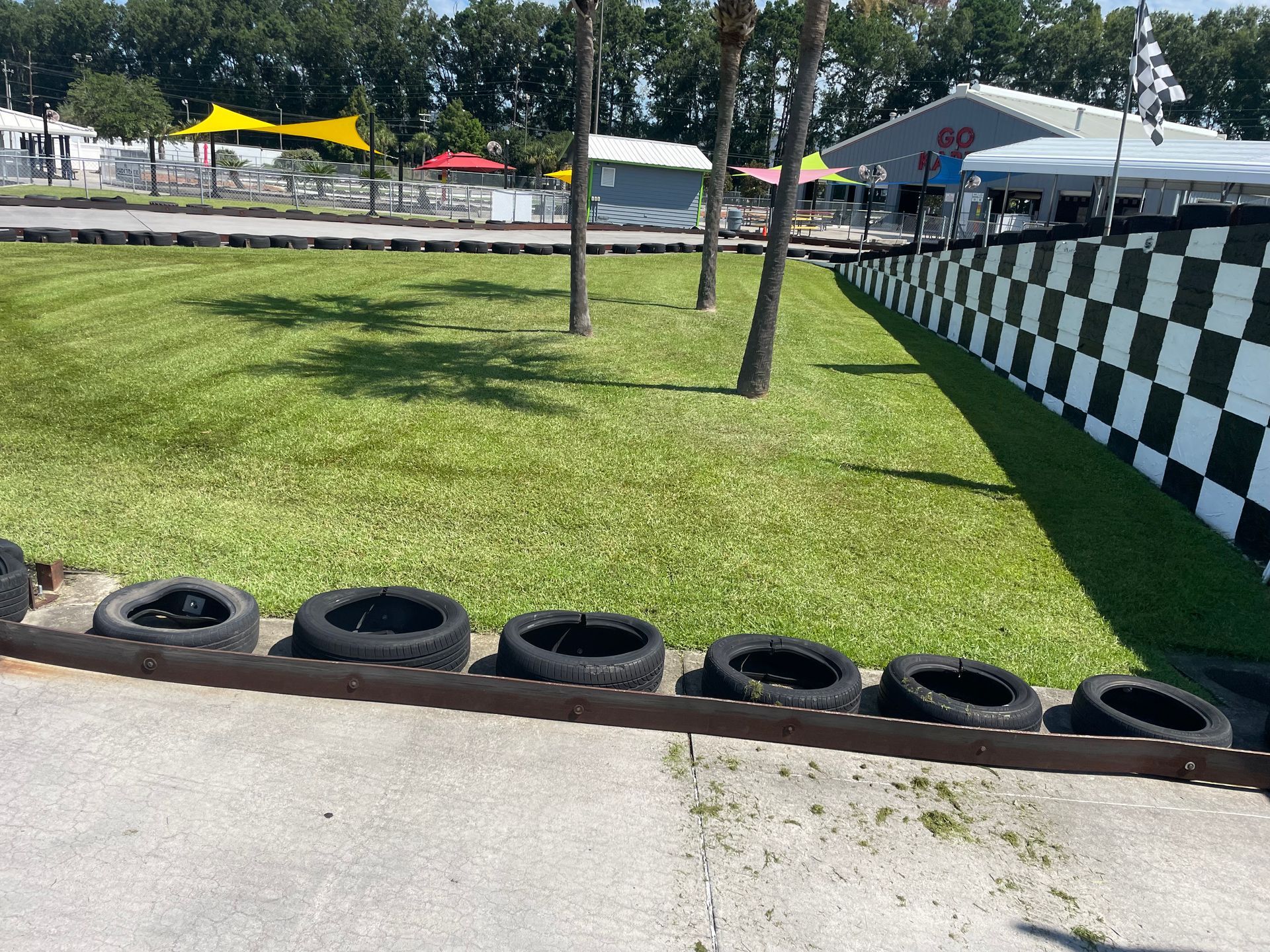 A race track with tires on the side of it and a checkered wall.