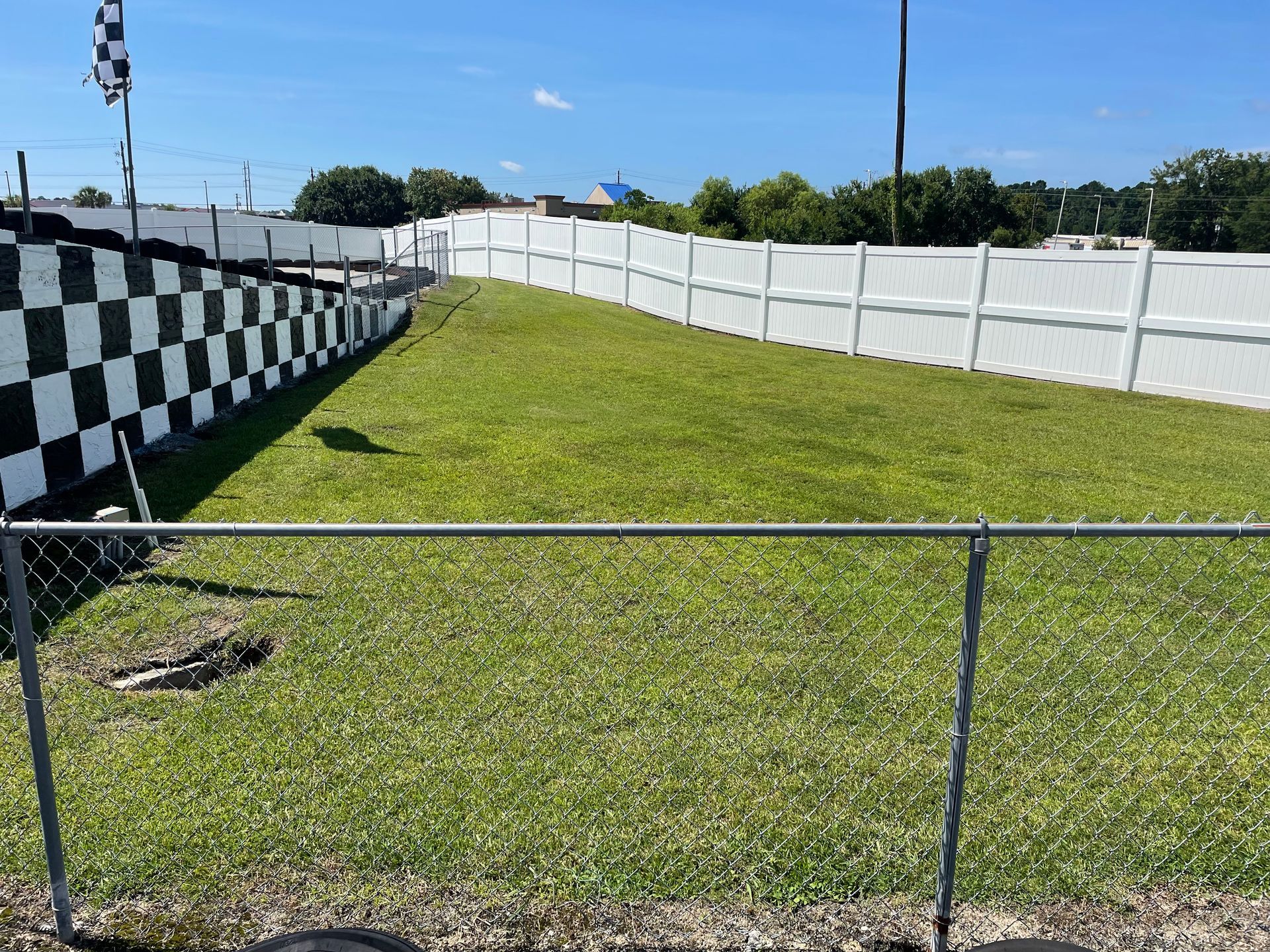 A black and white checkered fence surrounds a lush green field.