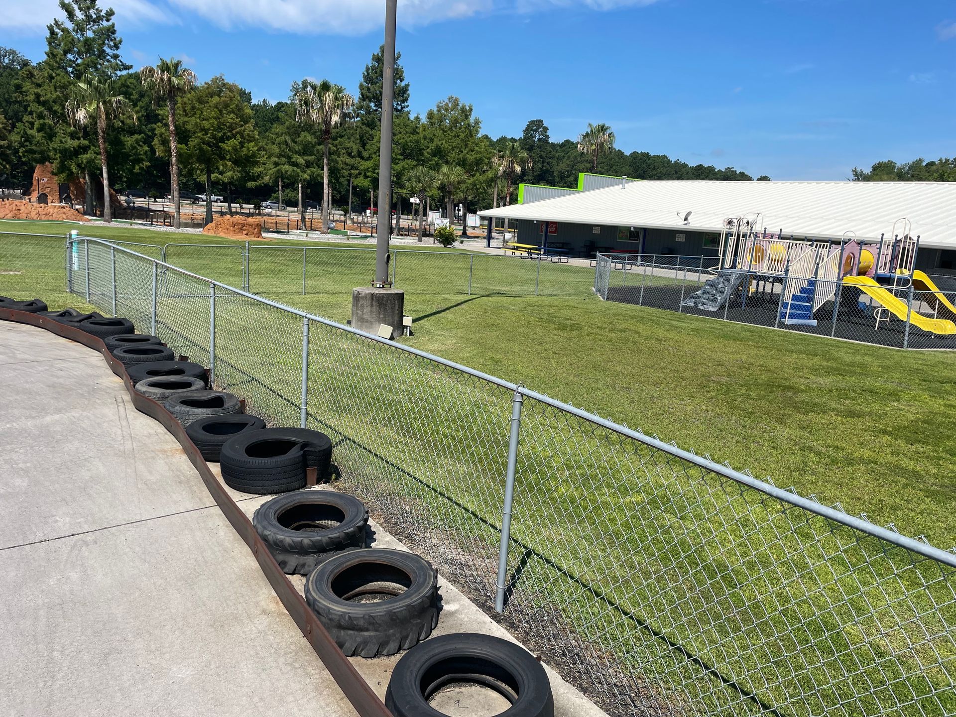 A row of tires on the side of a road next to a chain link fence.