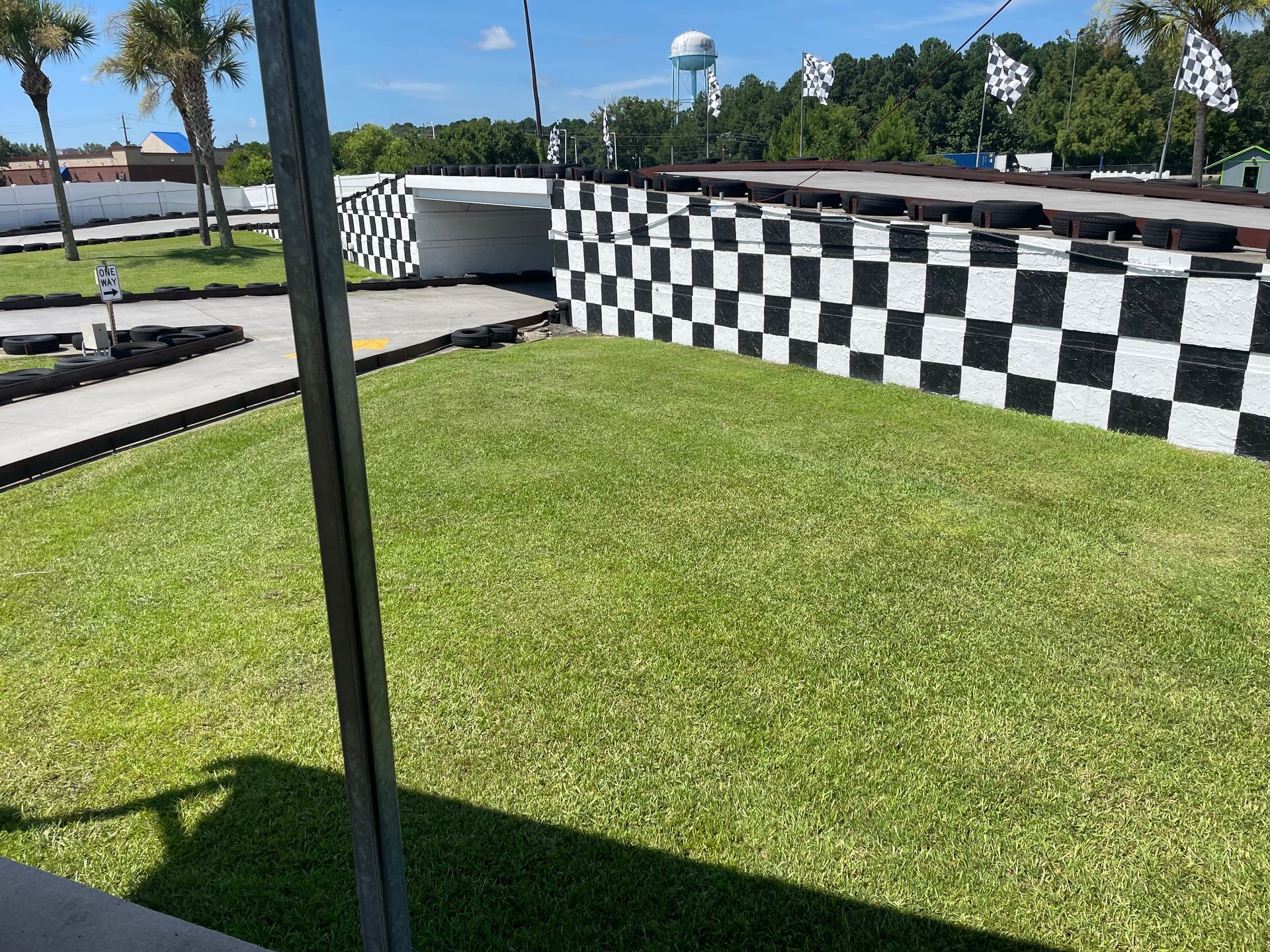 A black and white checkered wall is in the middle of a lush green field.