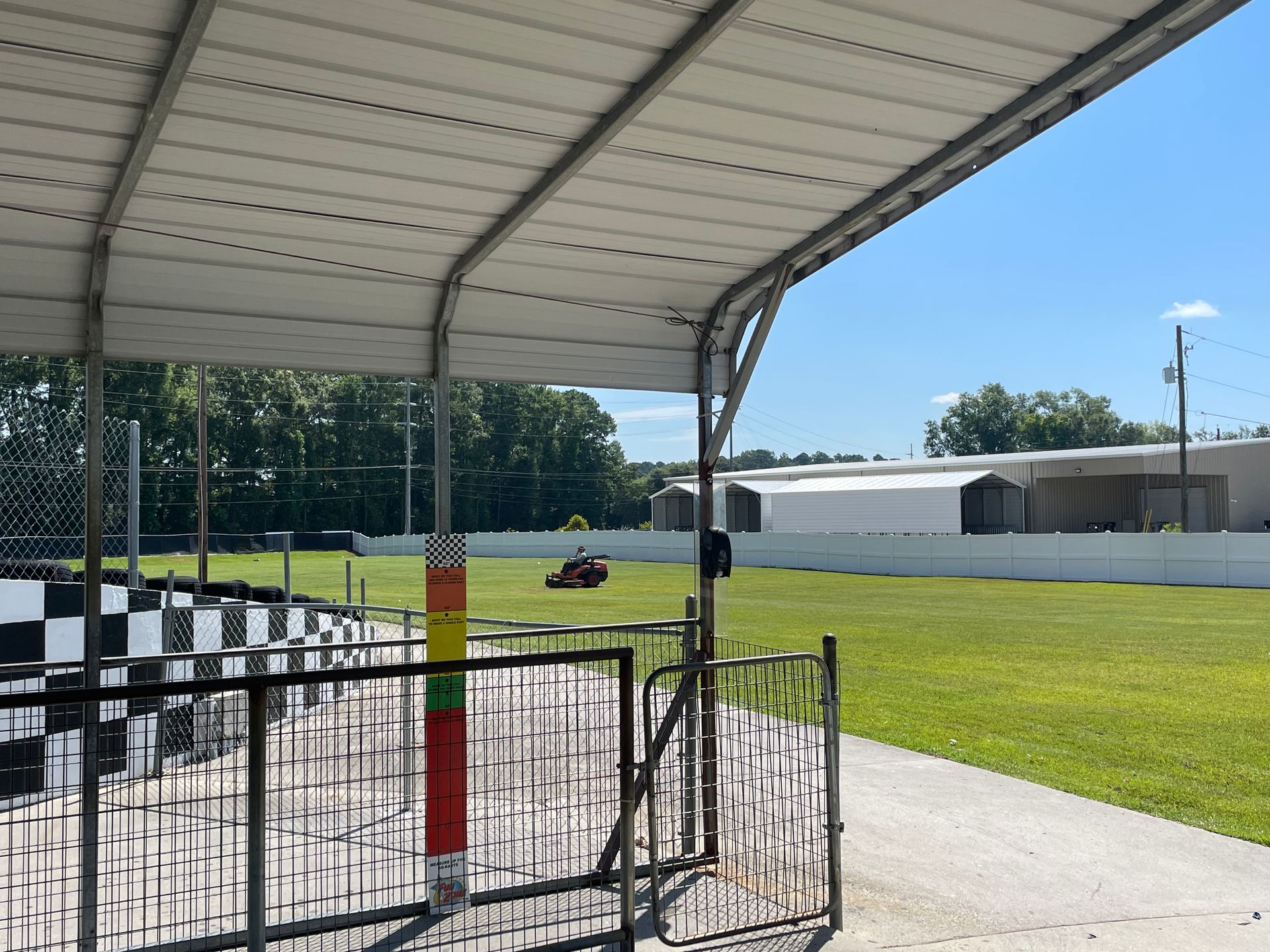 A person is riding a go kart on a track under a canopy.