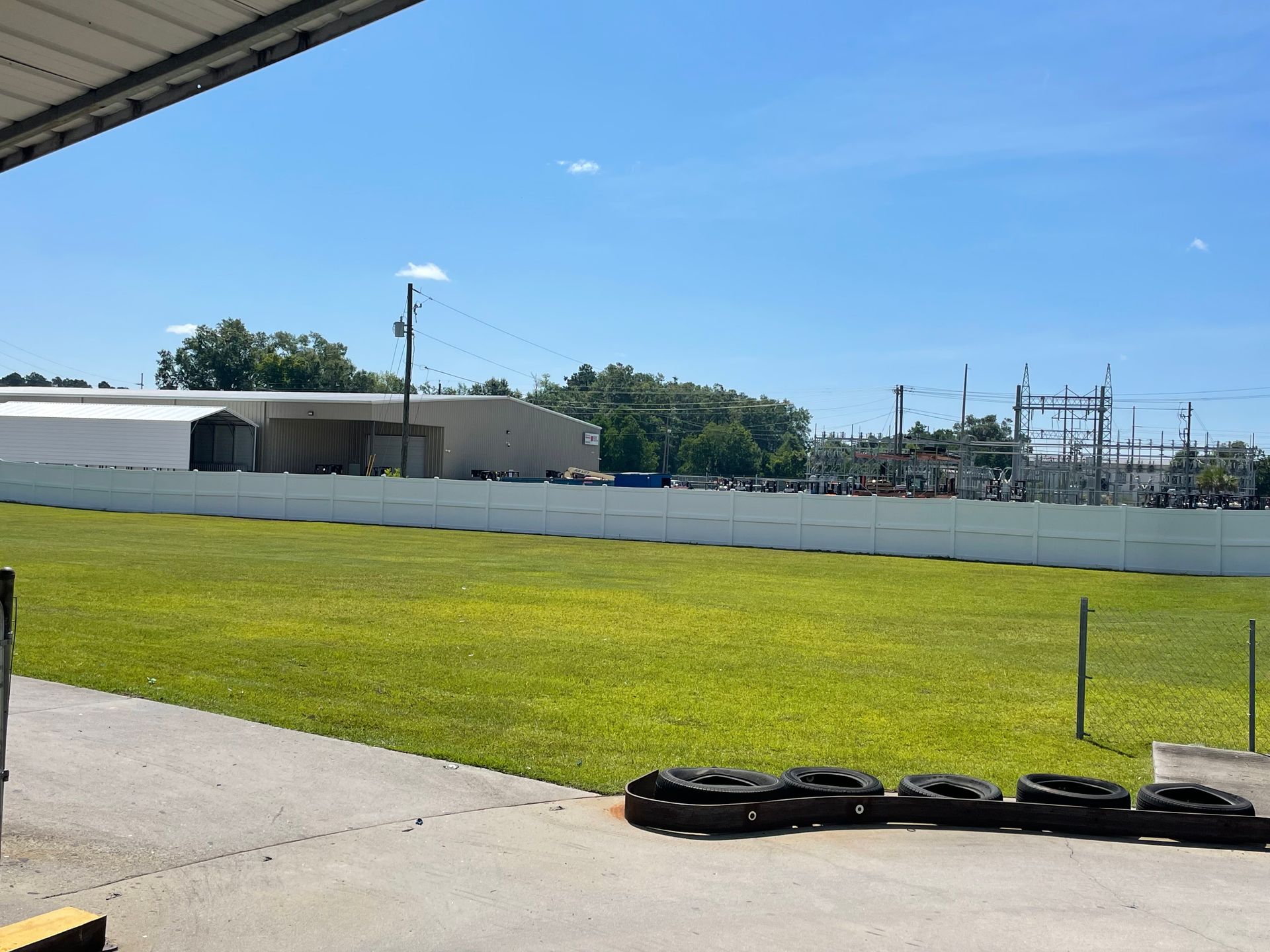 A row of tires are lined up in front of a grassy field.