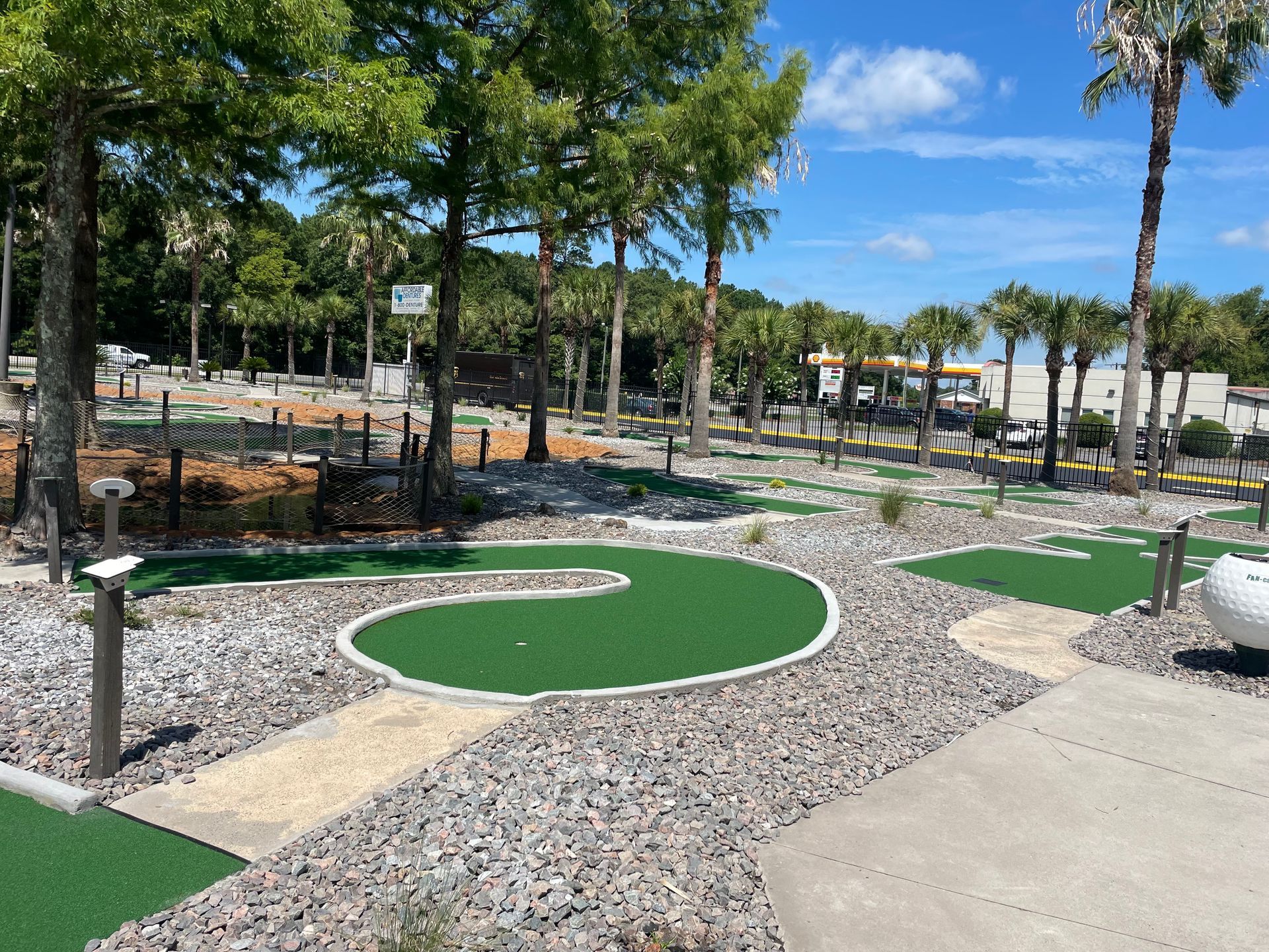 A small golf course in a park with palm trees in the background.