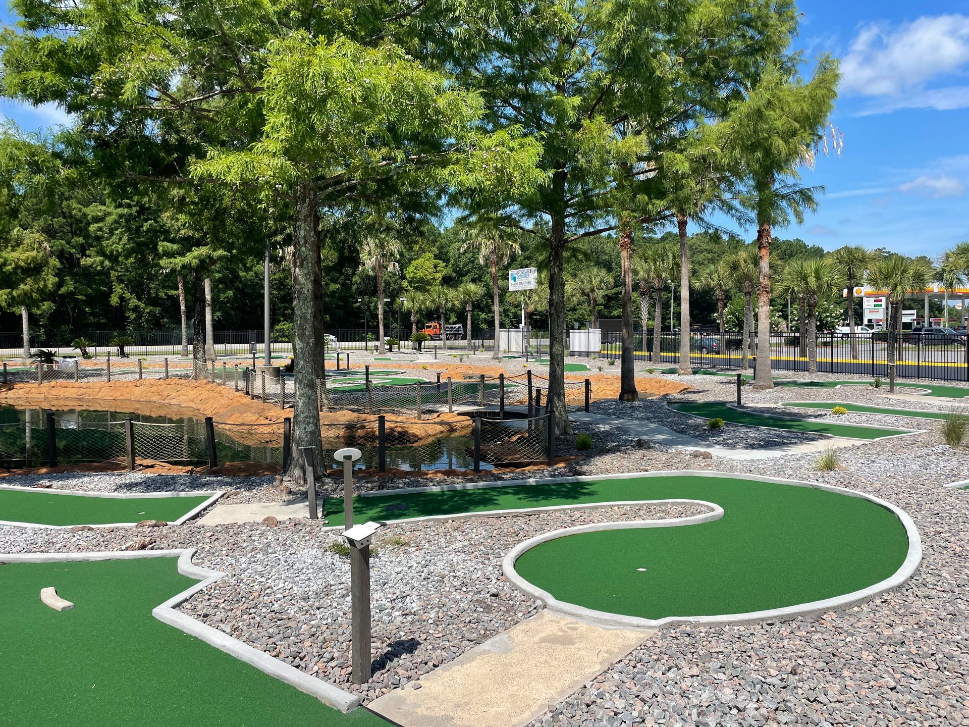A miniature golf course in a park with trees in the background.