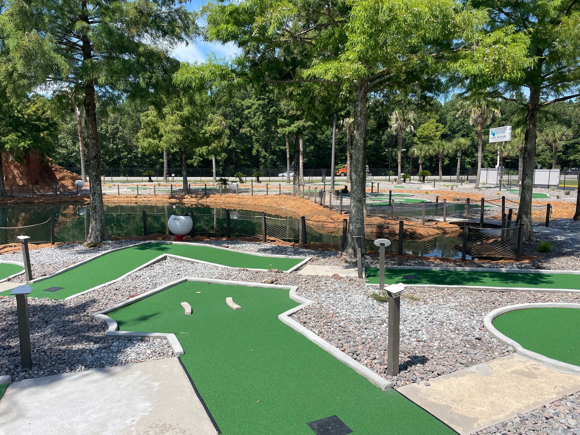 A mini golf course in a park with trees in the background.