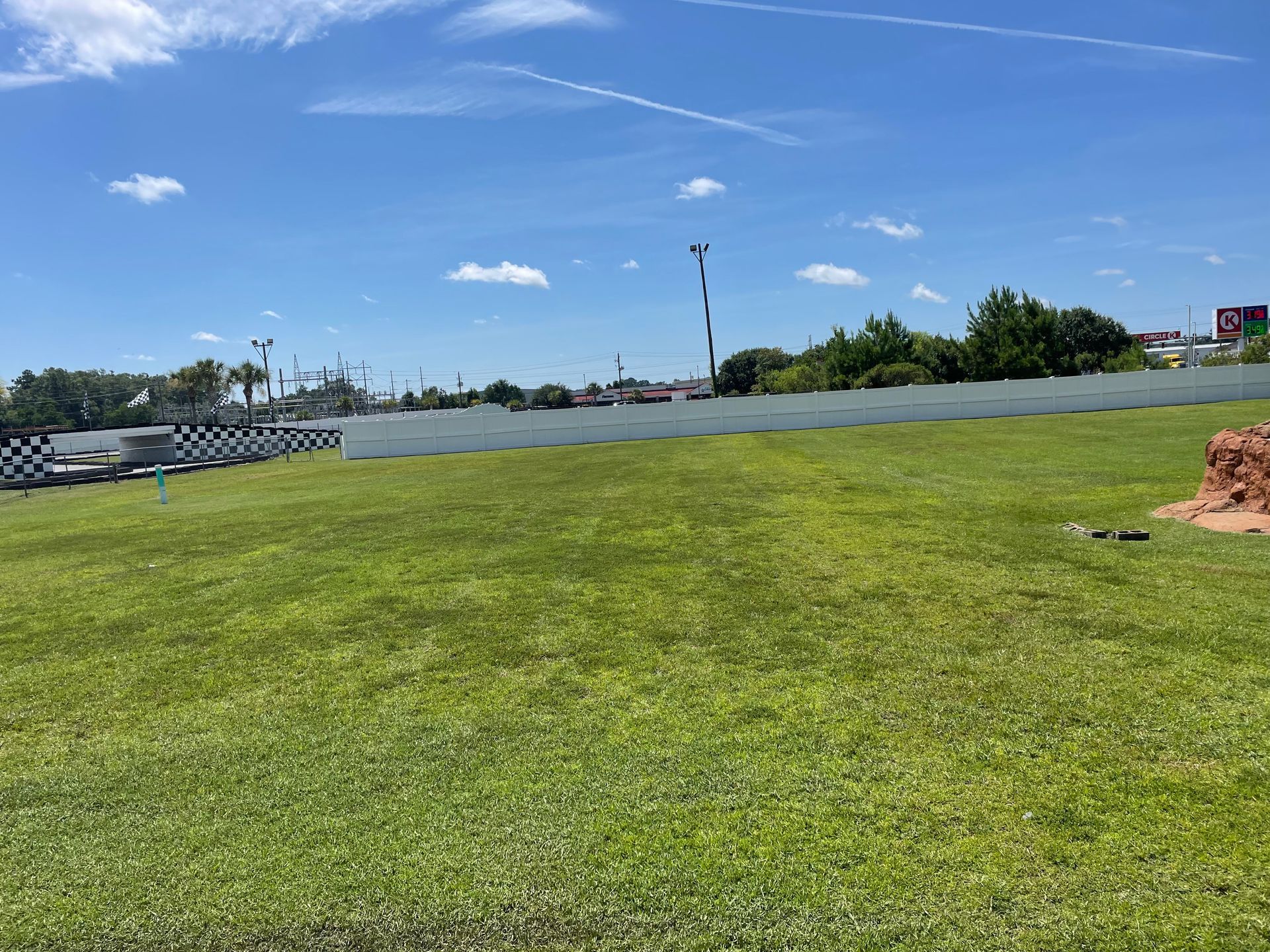 A large grassy field with a fence in the background on a sunny day.