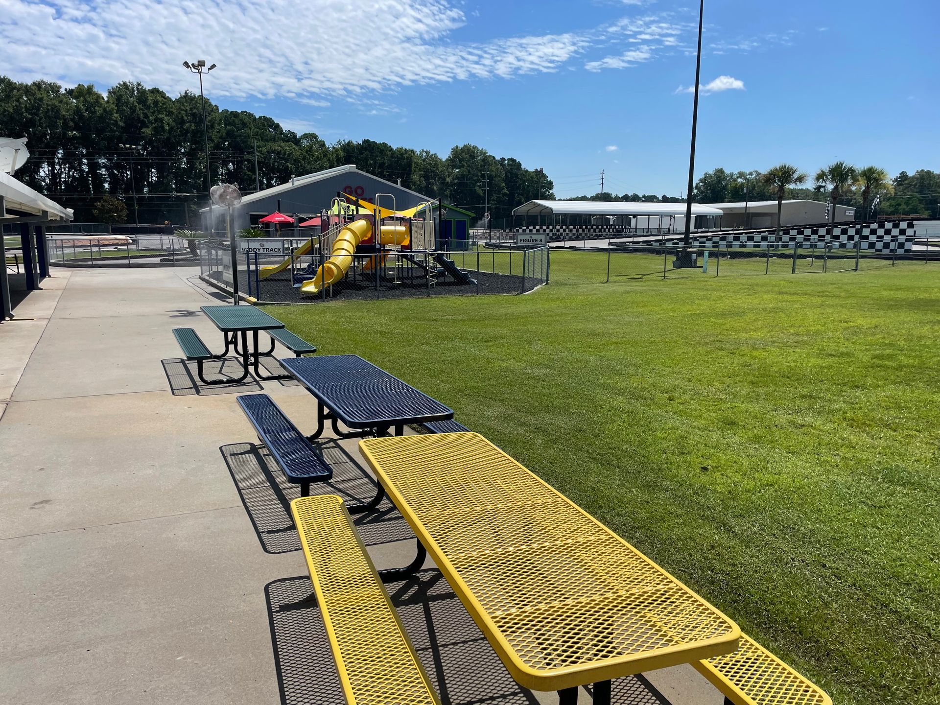 A picnic table and benches in a park with a playground in the background