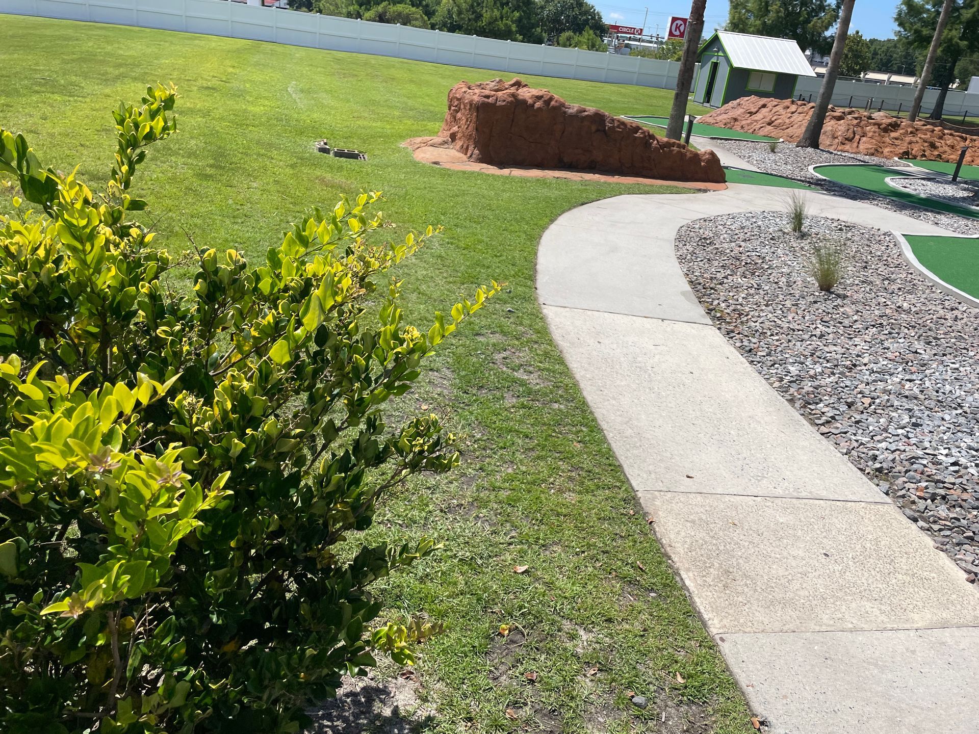 A concrete walkway leading to a golf course in a park