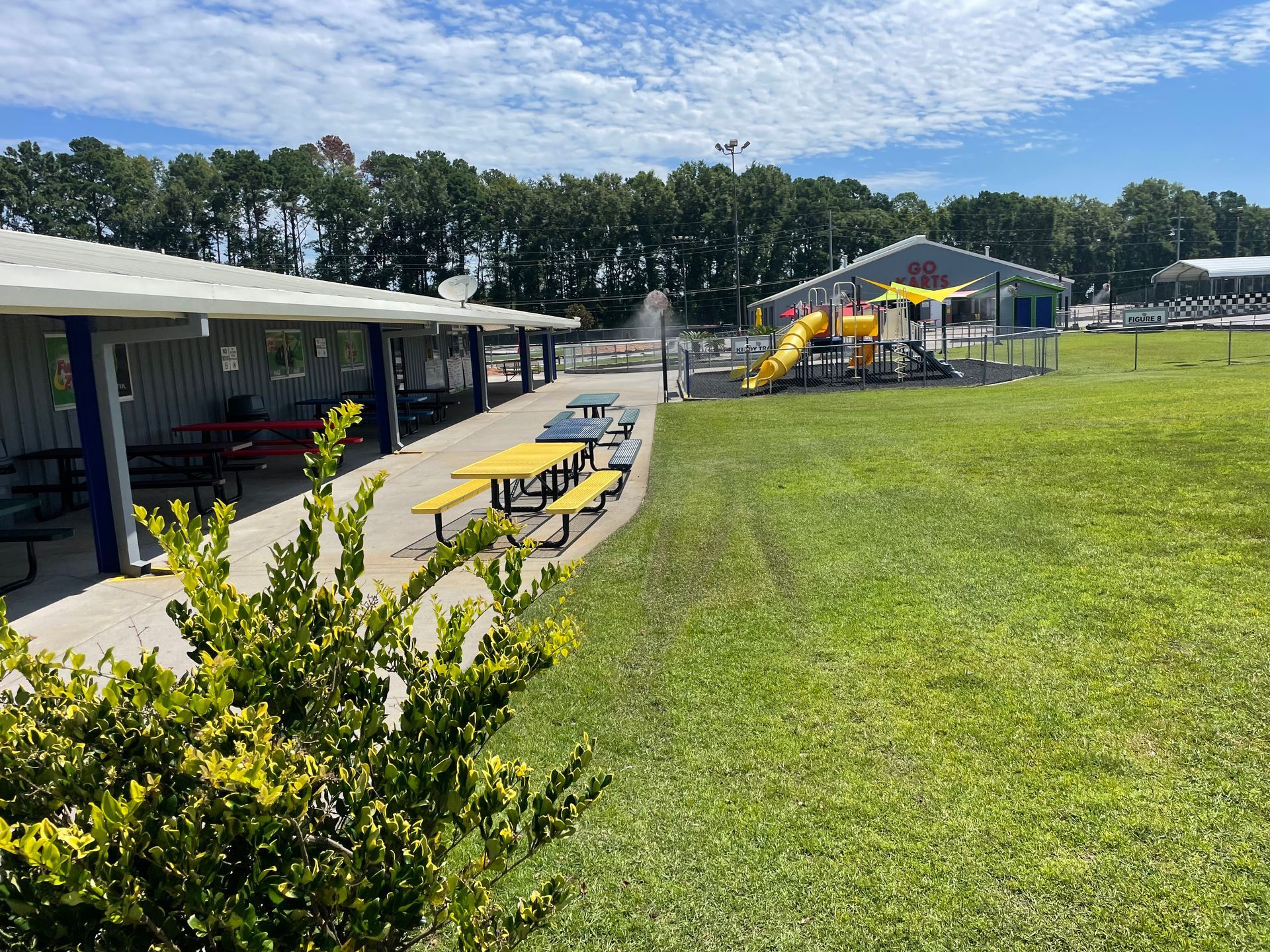 A picnic area with tables and benches in front of a playground.