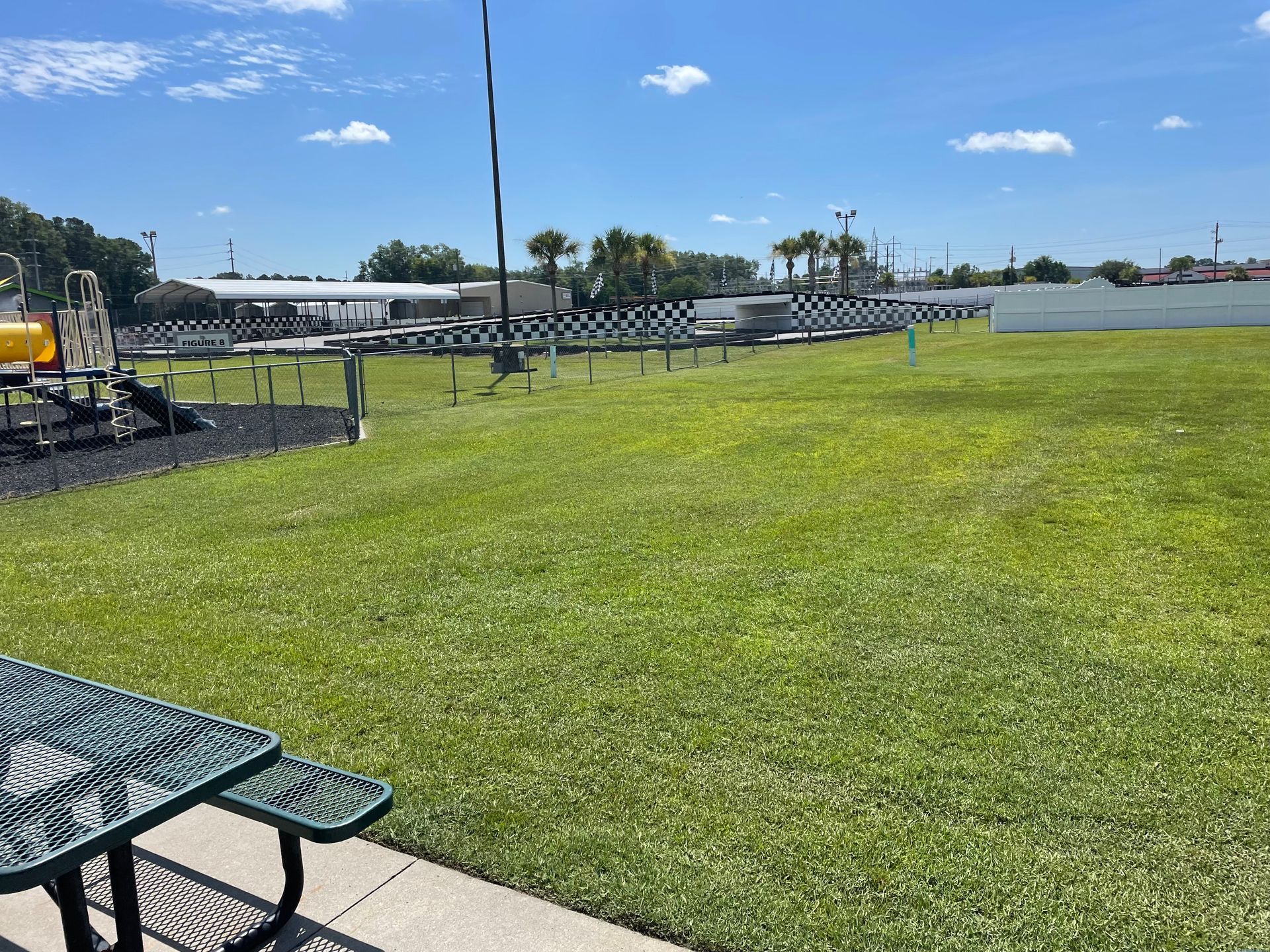 There is a picnic table in the foreground and a playground in the background.