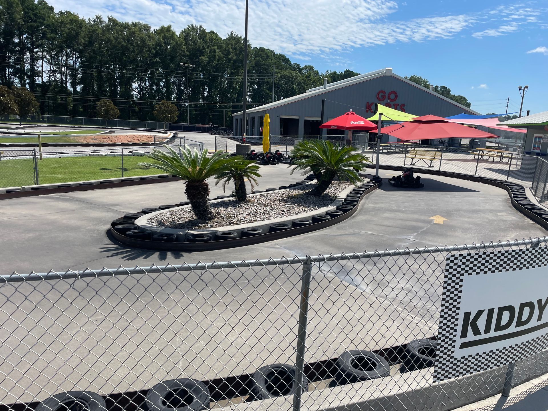 A go kart track behind a chain link fence with a sign that says kiddy