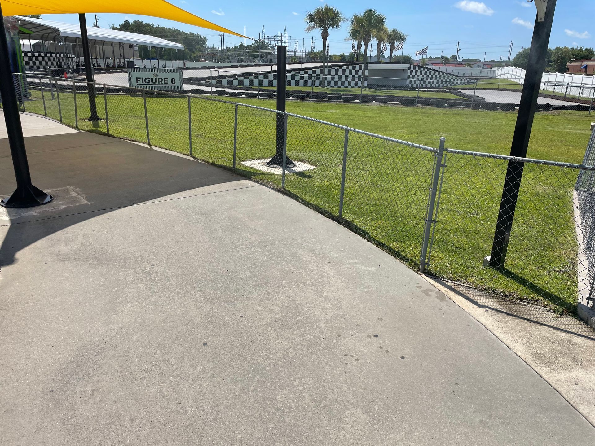 A chain link fence surrounds a lush green field.