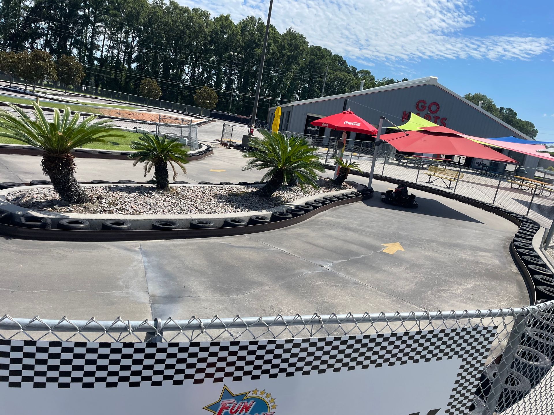 A go kart track with umbrellas and a building in the background