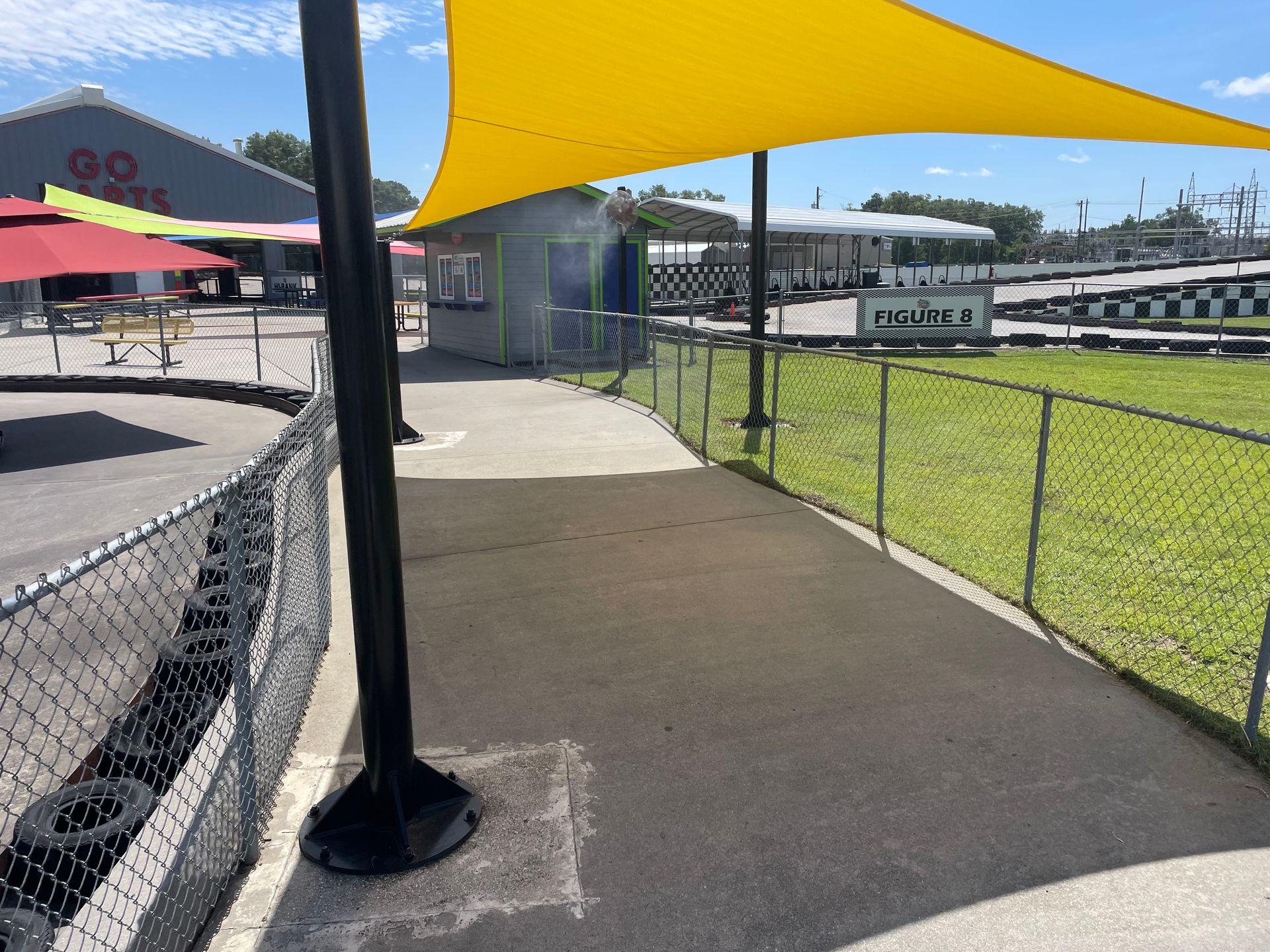 A yellow umbrella is hanging over a walkway next to a chain link fence.