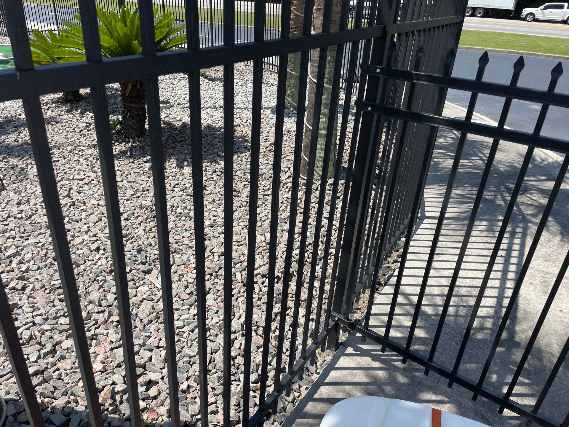 A black metal fence is surrounding a gravel area.