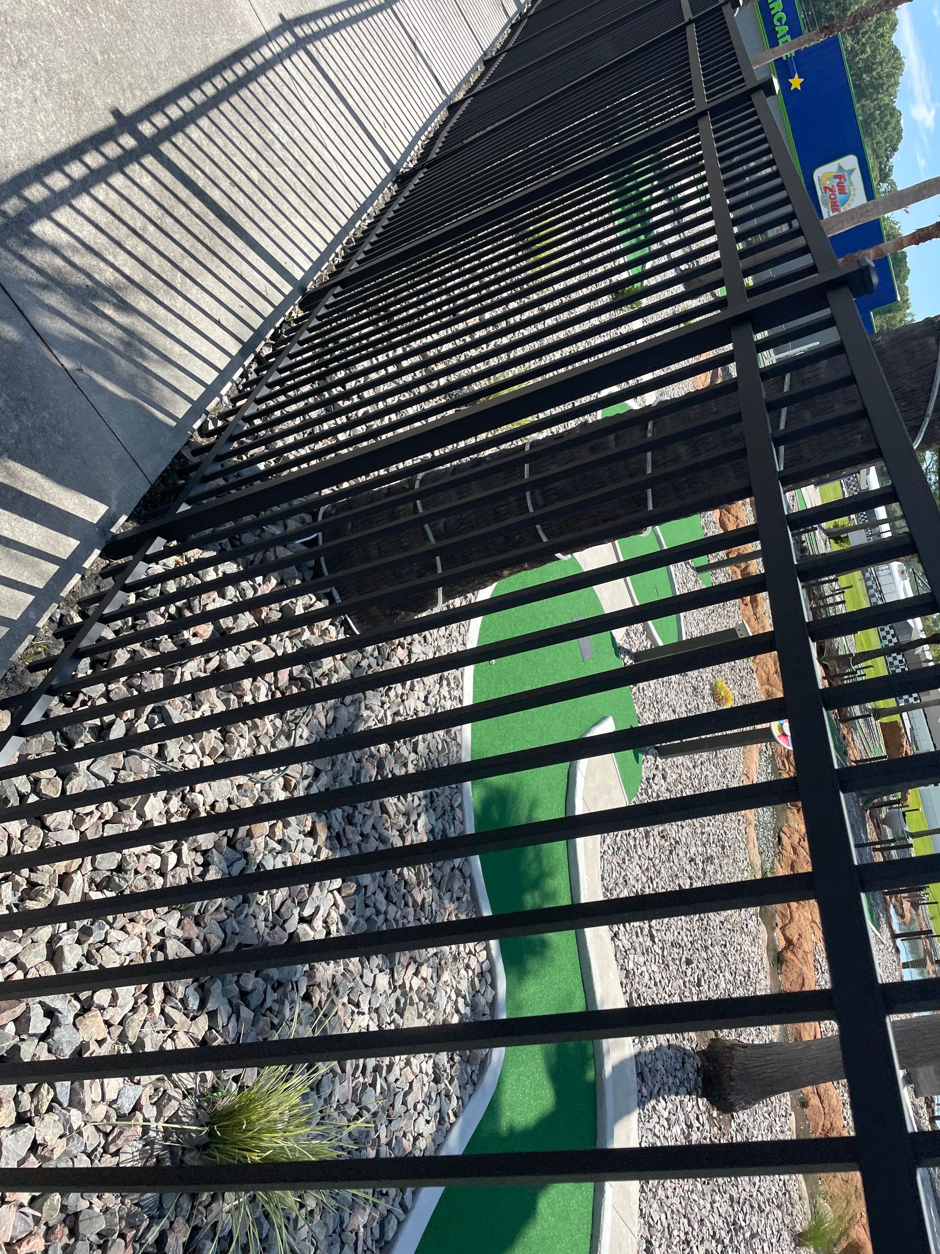 A black metal fence surrounds a small golf course