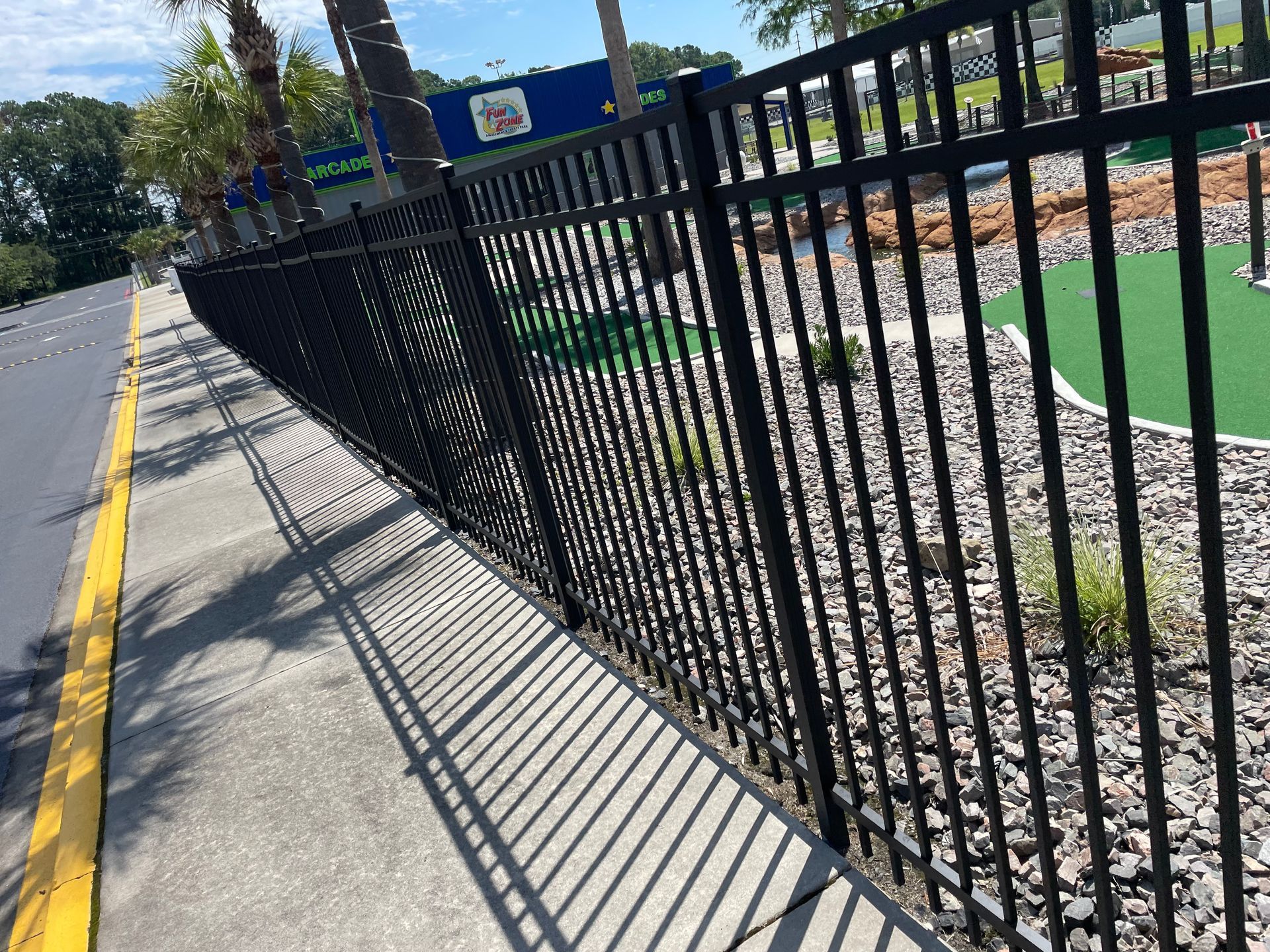 A black metal fence along a sidewalk next to a road.