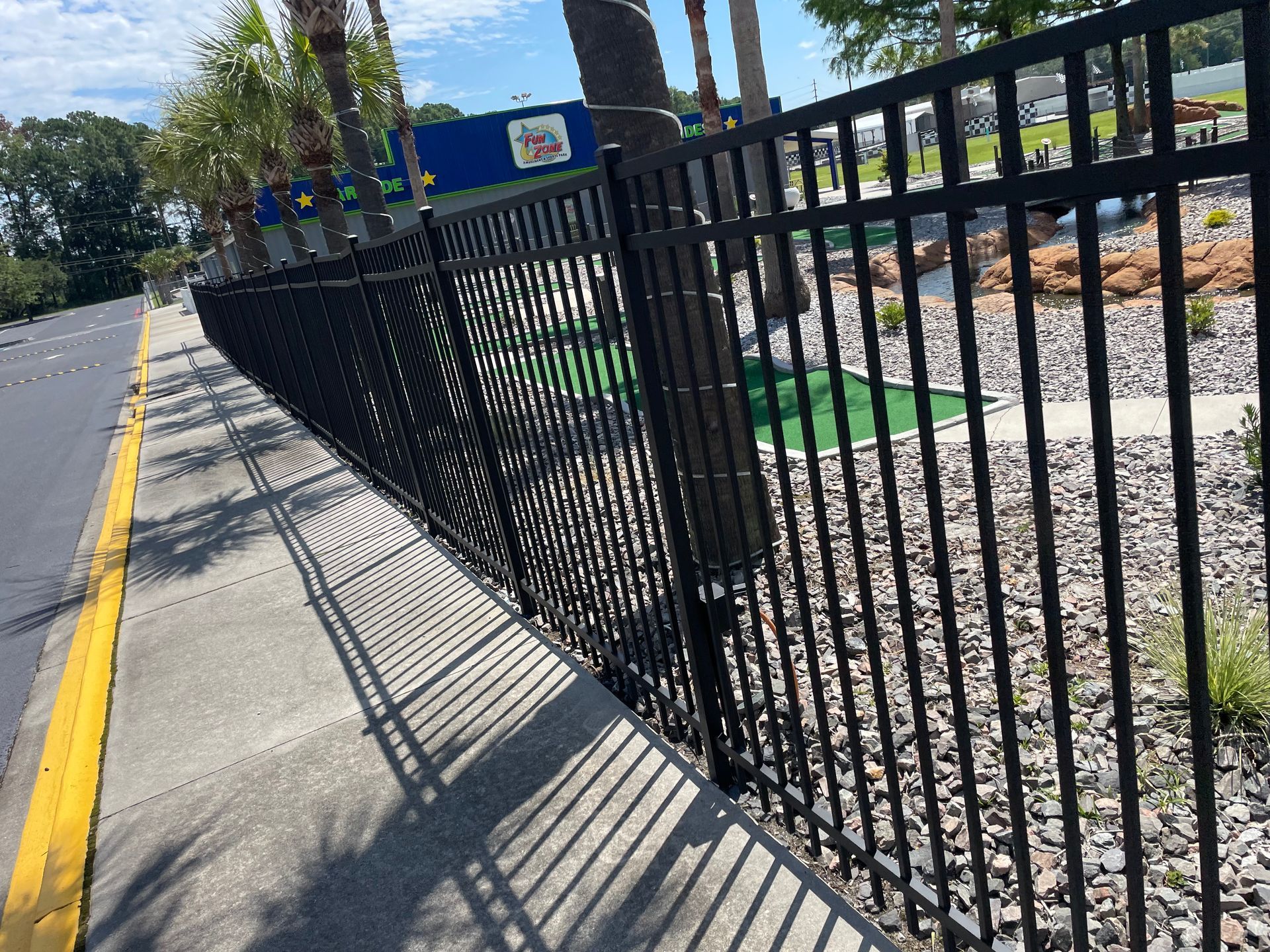 A black metal fence along a sidewalk next to a road.
