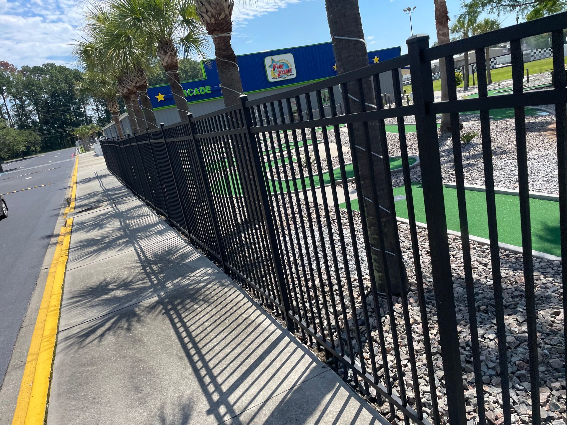 A black fence along a sidewalk next to a road.