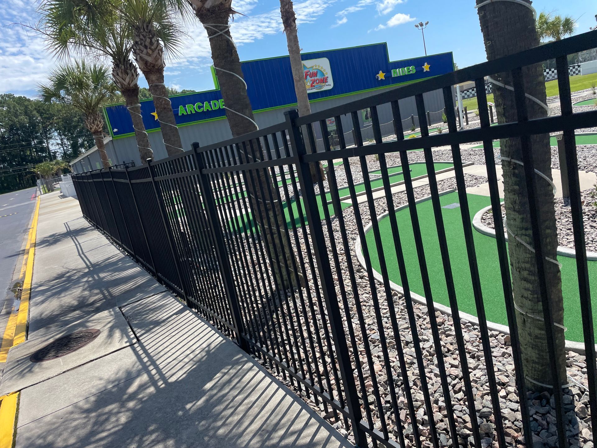A black metal fence surrounds a mini golf course.