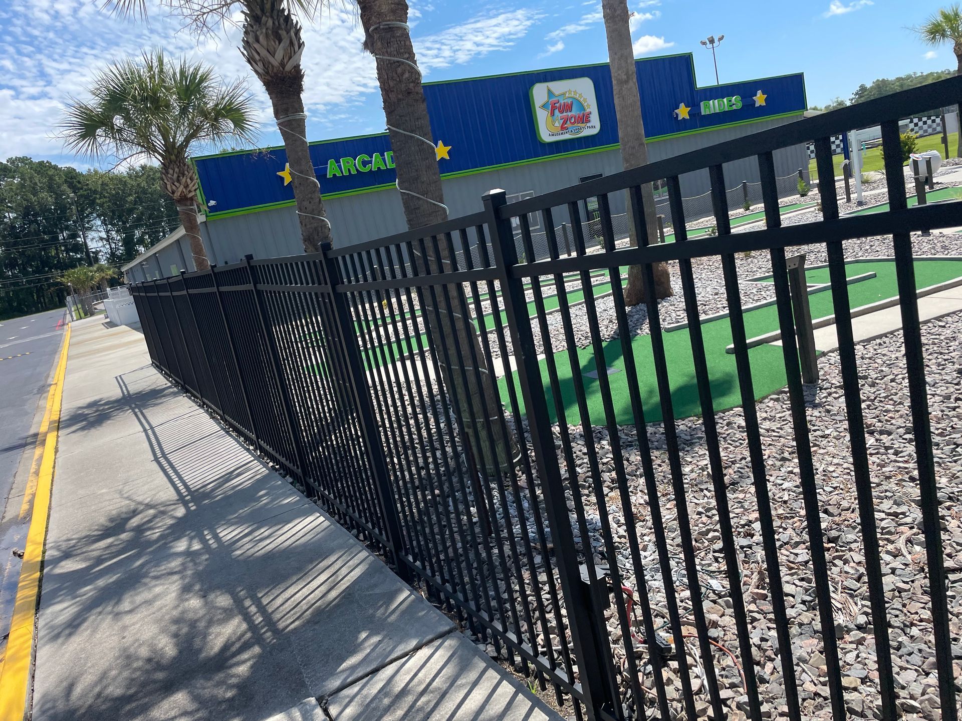 A black metal fence surrounds a small golf course.