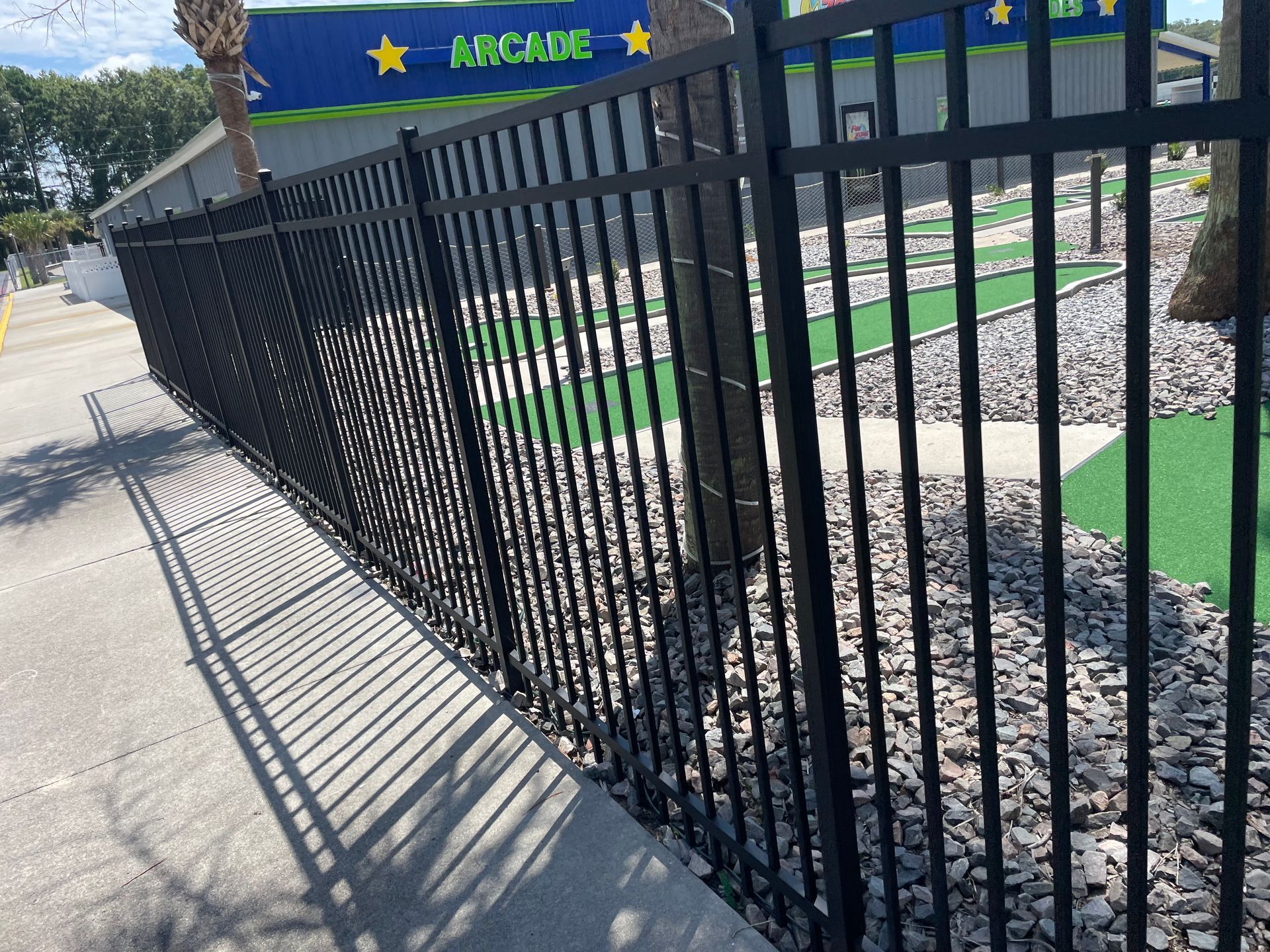 A black metal fence surrounds a small golf course.