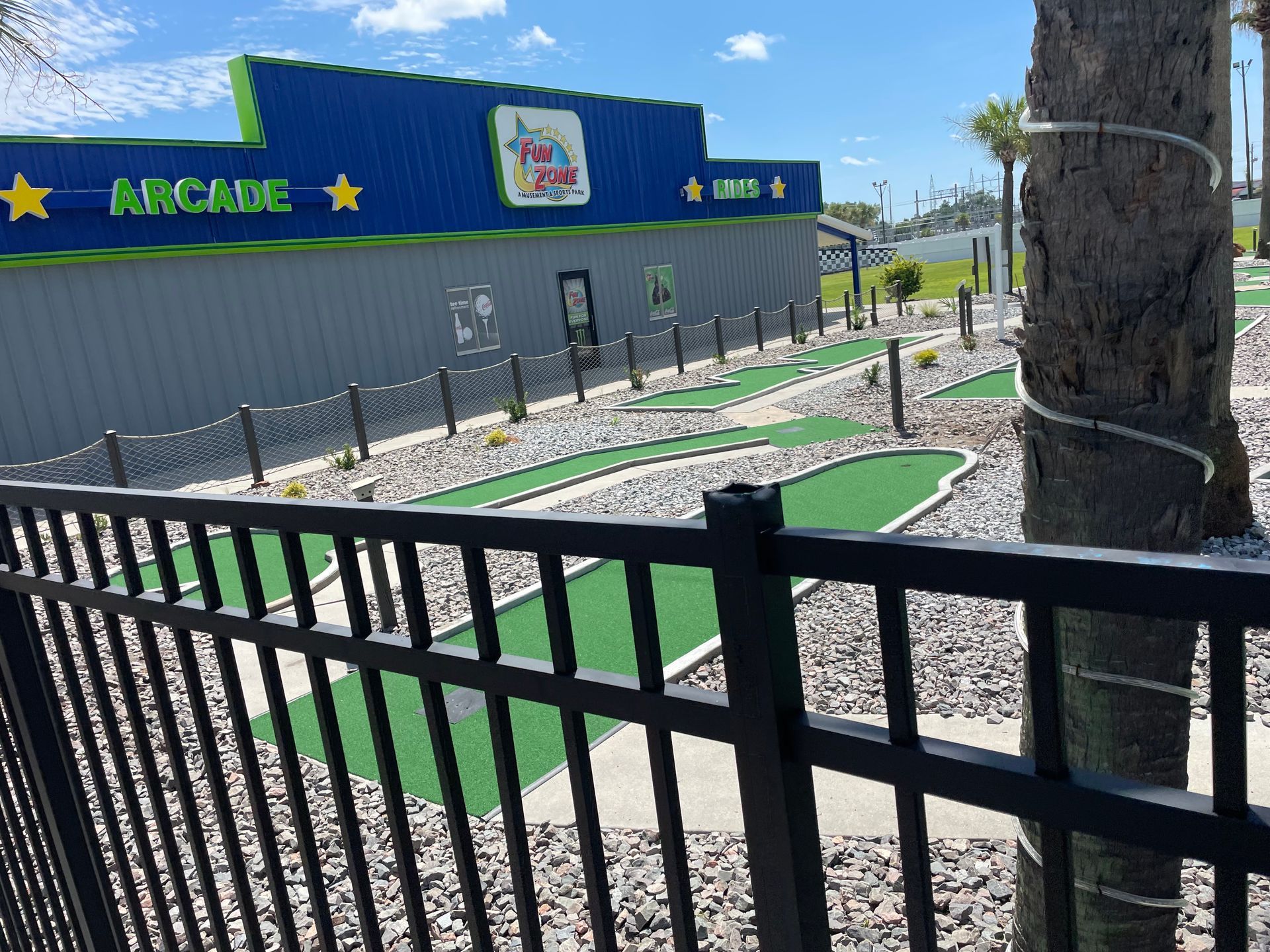 A fence surrounds a mini golf course in front of a building.
