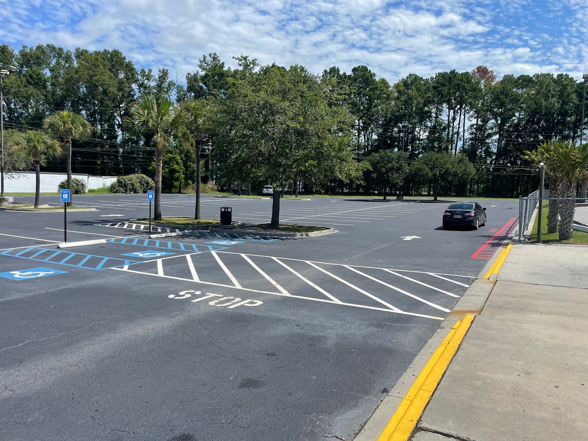 A car is parked in a handicapped parking spot in a parking lot.