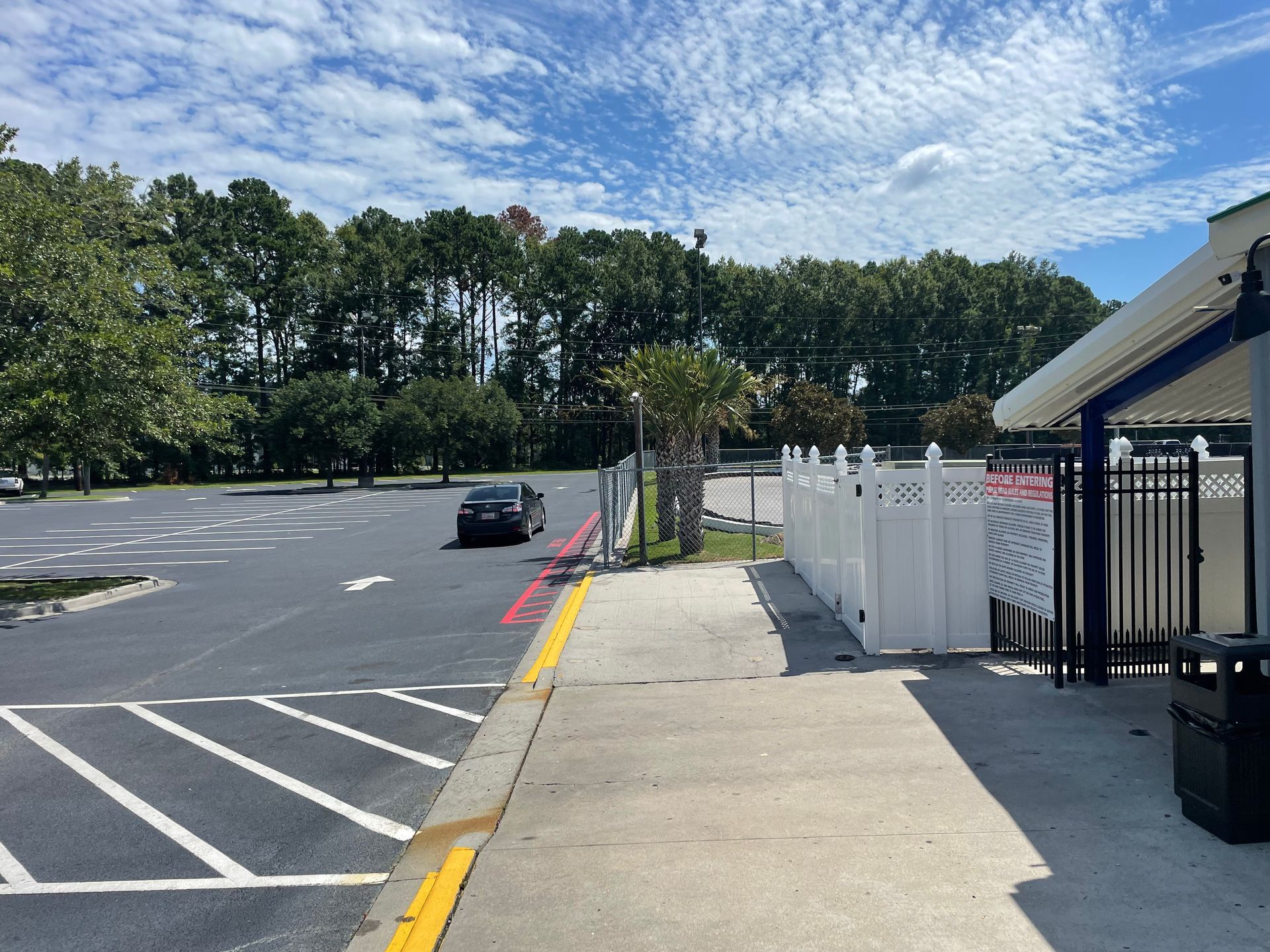 A car is parked in a parking lot next to a sidewalk.