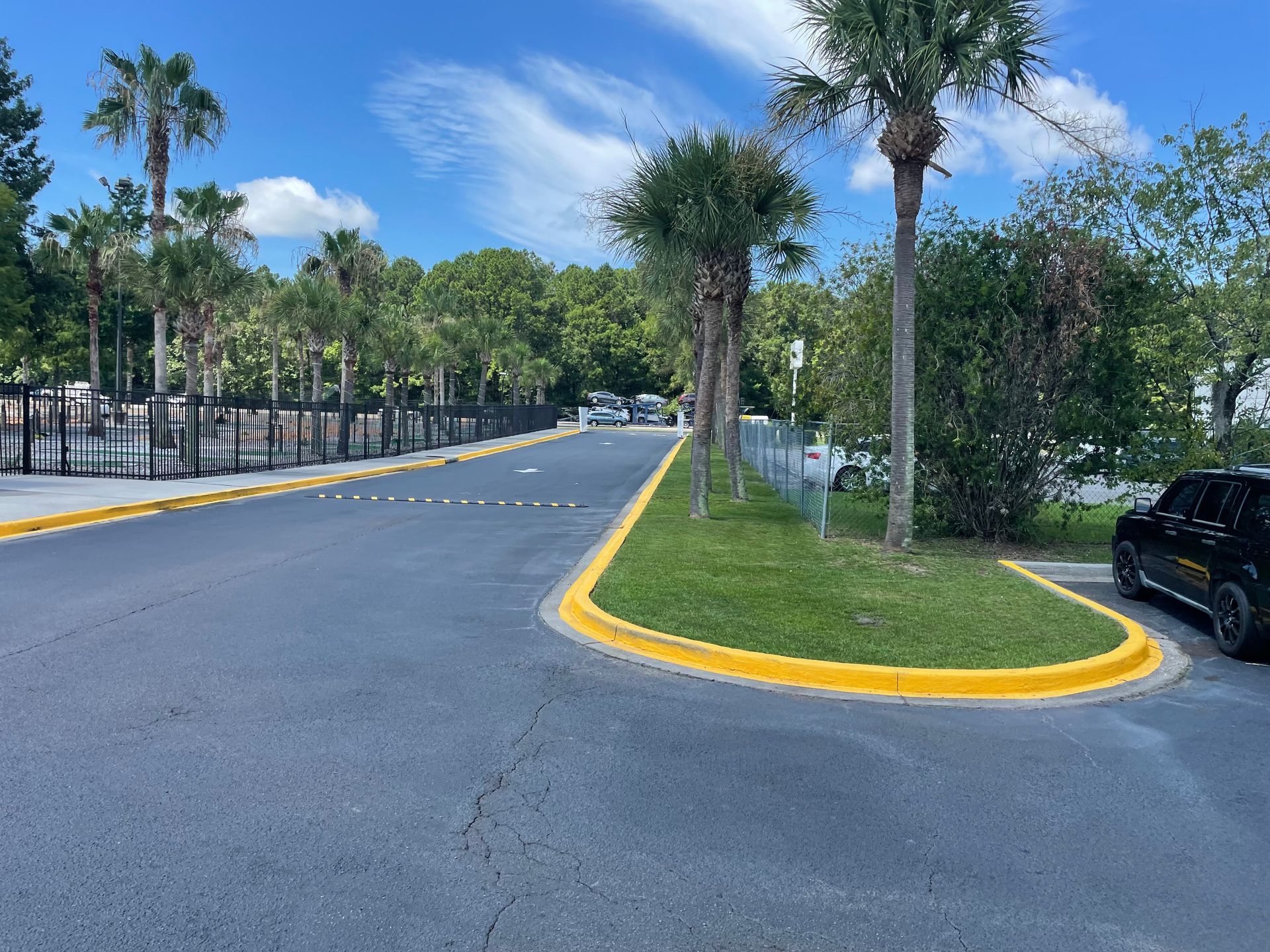 A black car is parked on the side of the road in a parking lot.