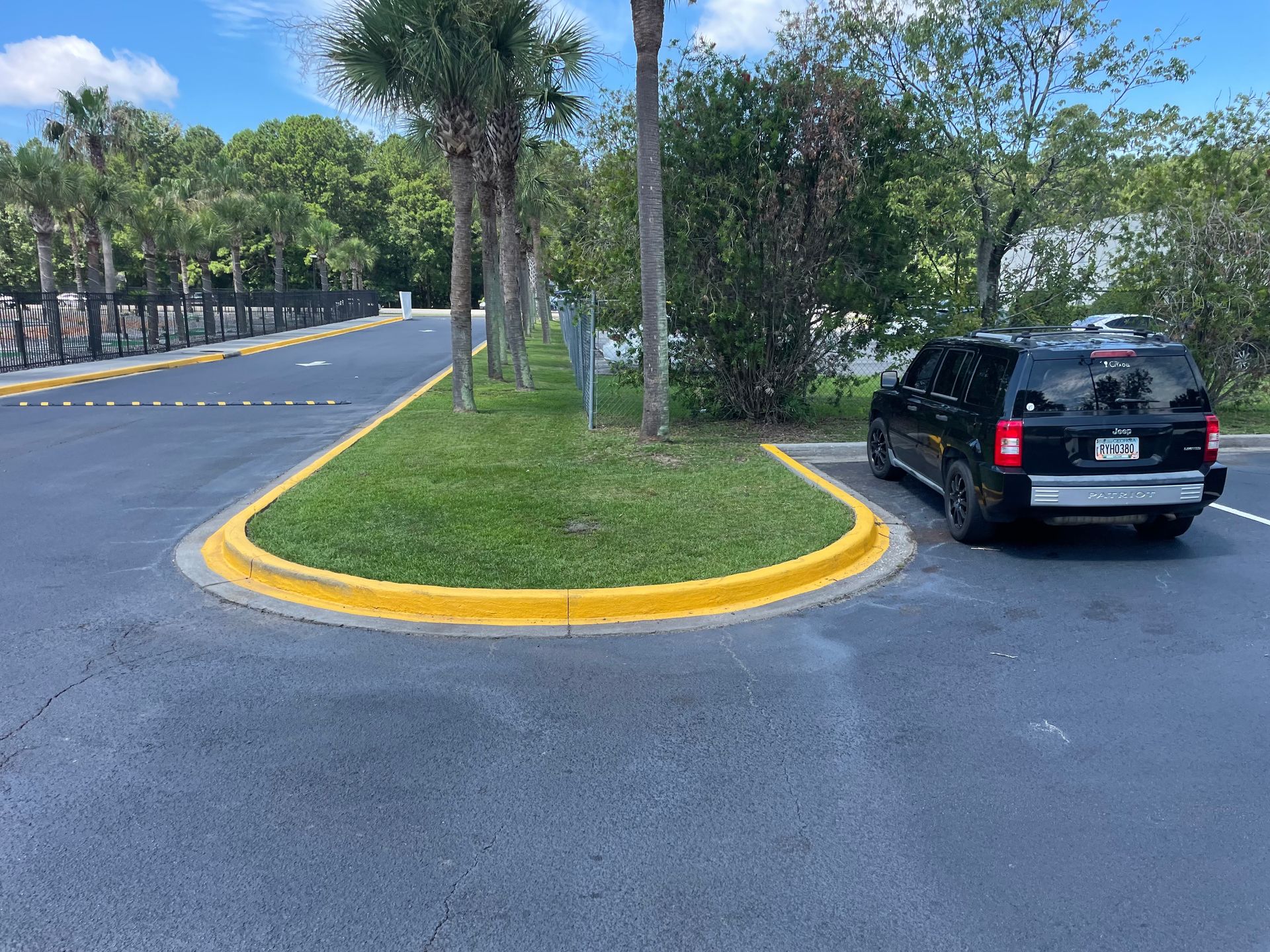 A black suv is parked in a parking lot next to a grassy curb.