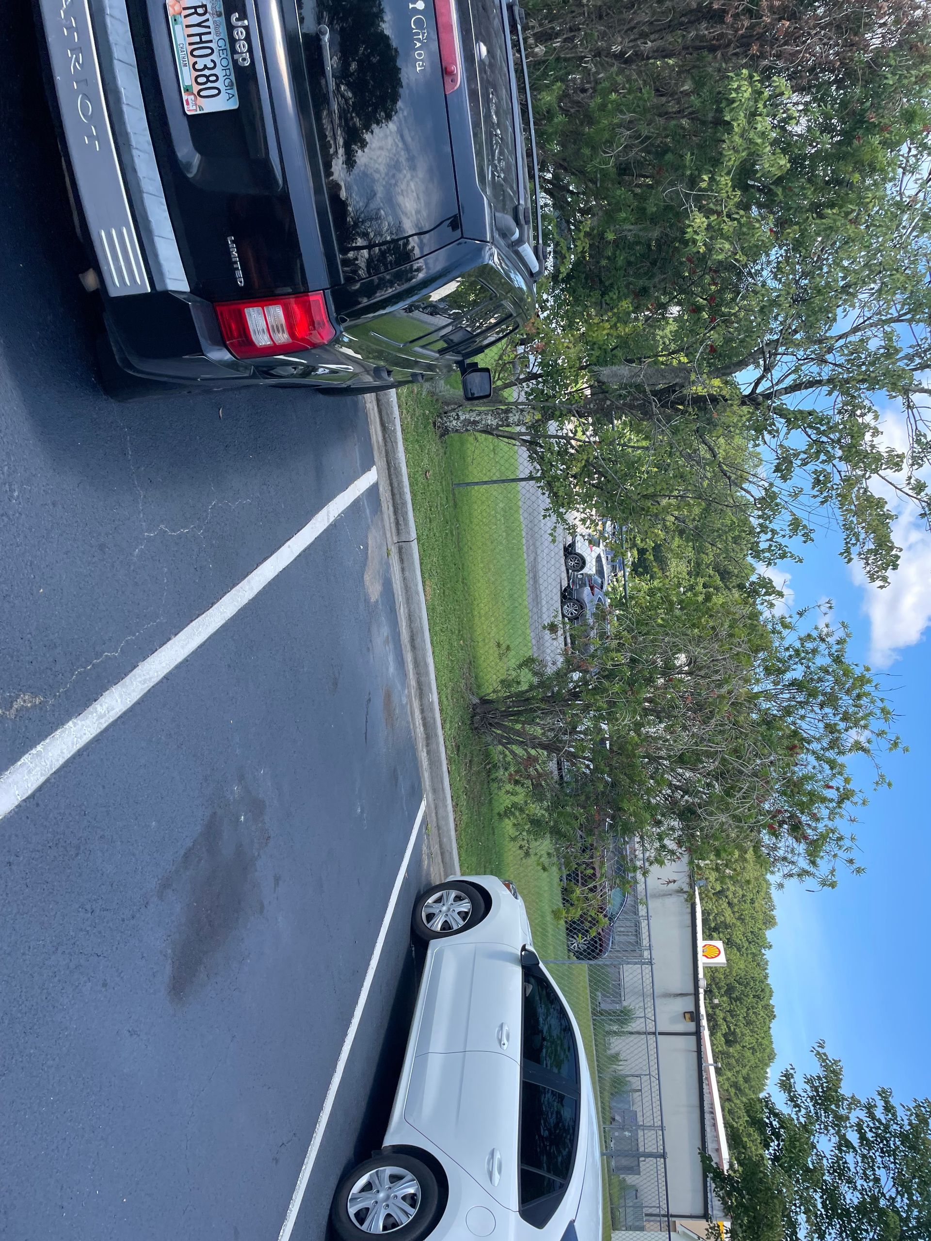 A white car is parked next to a black truck in a parking lot.