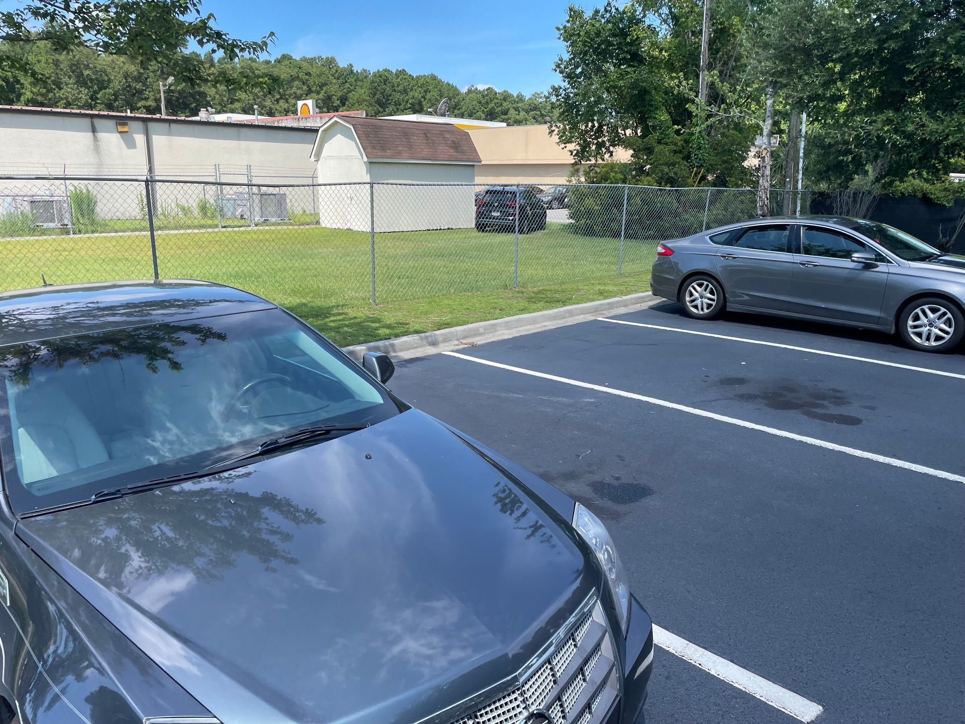 Two cars are parked in a parking lot with a barn in the background.