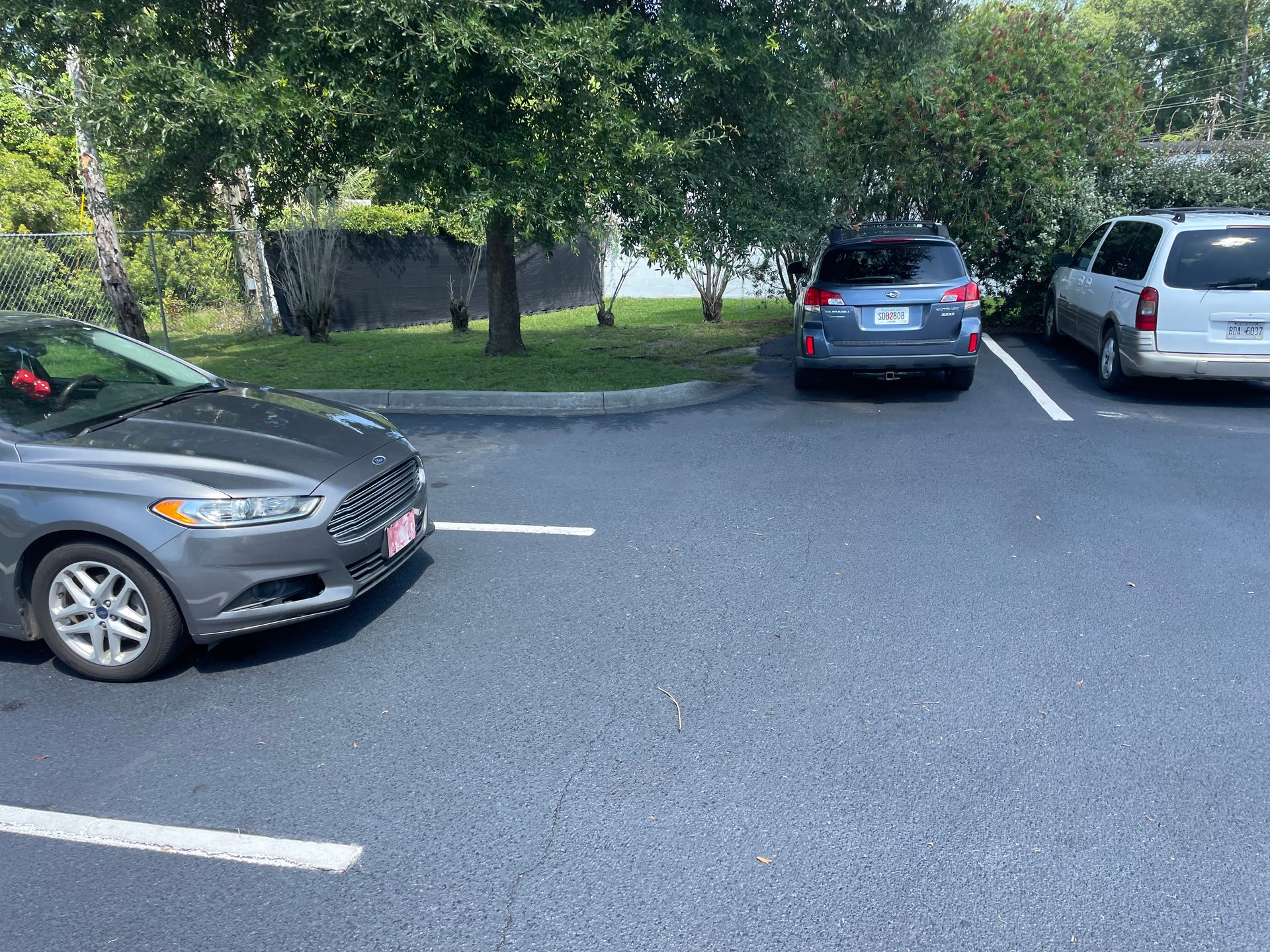 A gray car is parked in a parking lot next to a white van.