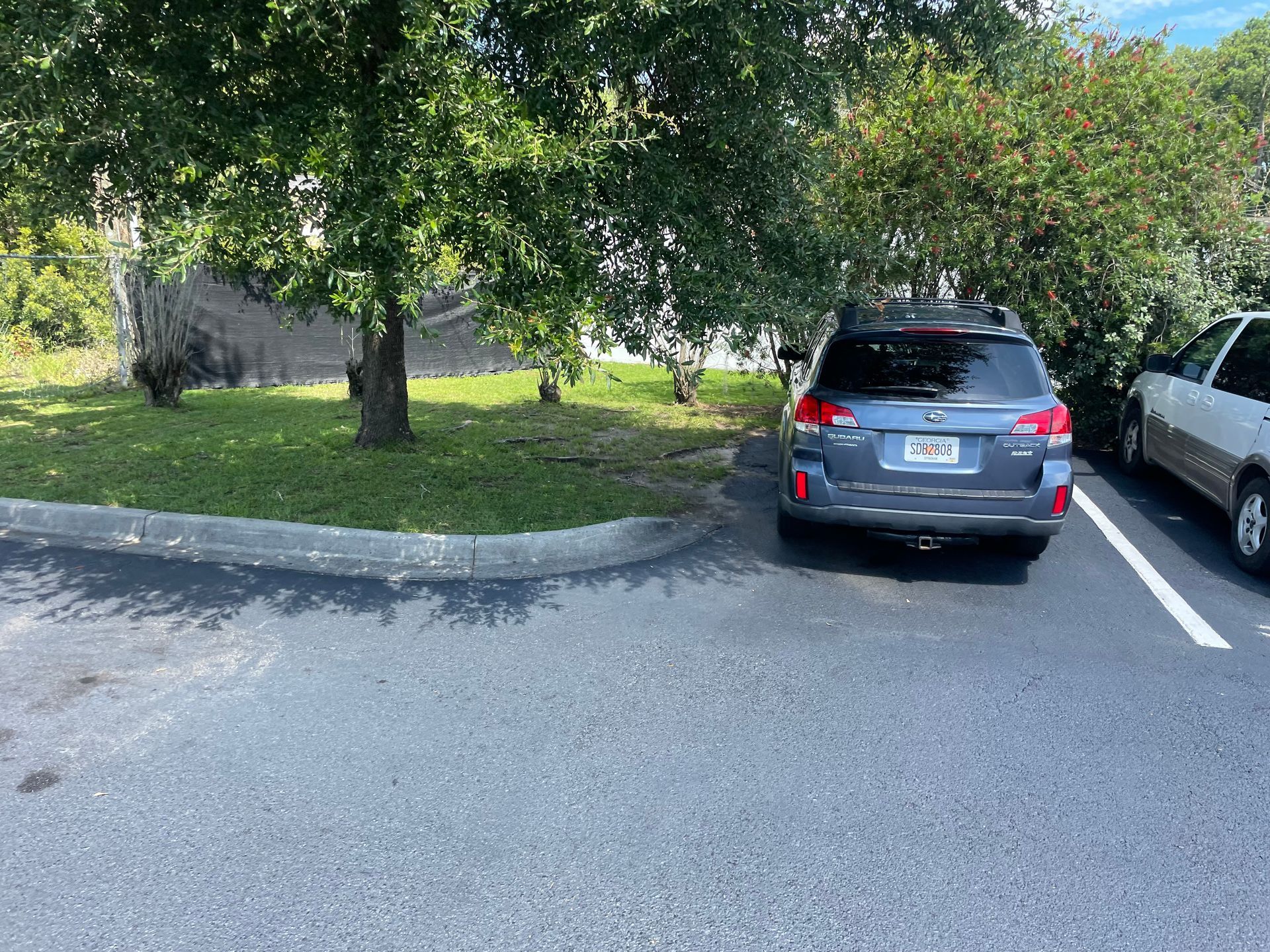 A car is parked in a parking lot next to a tree.