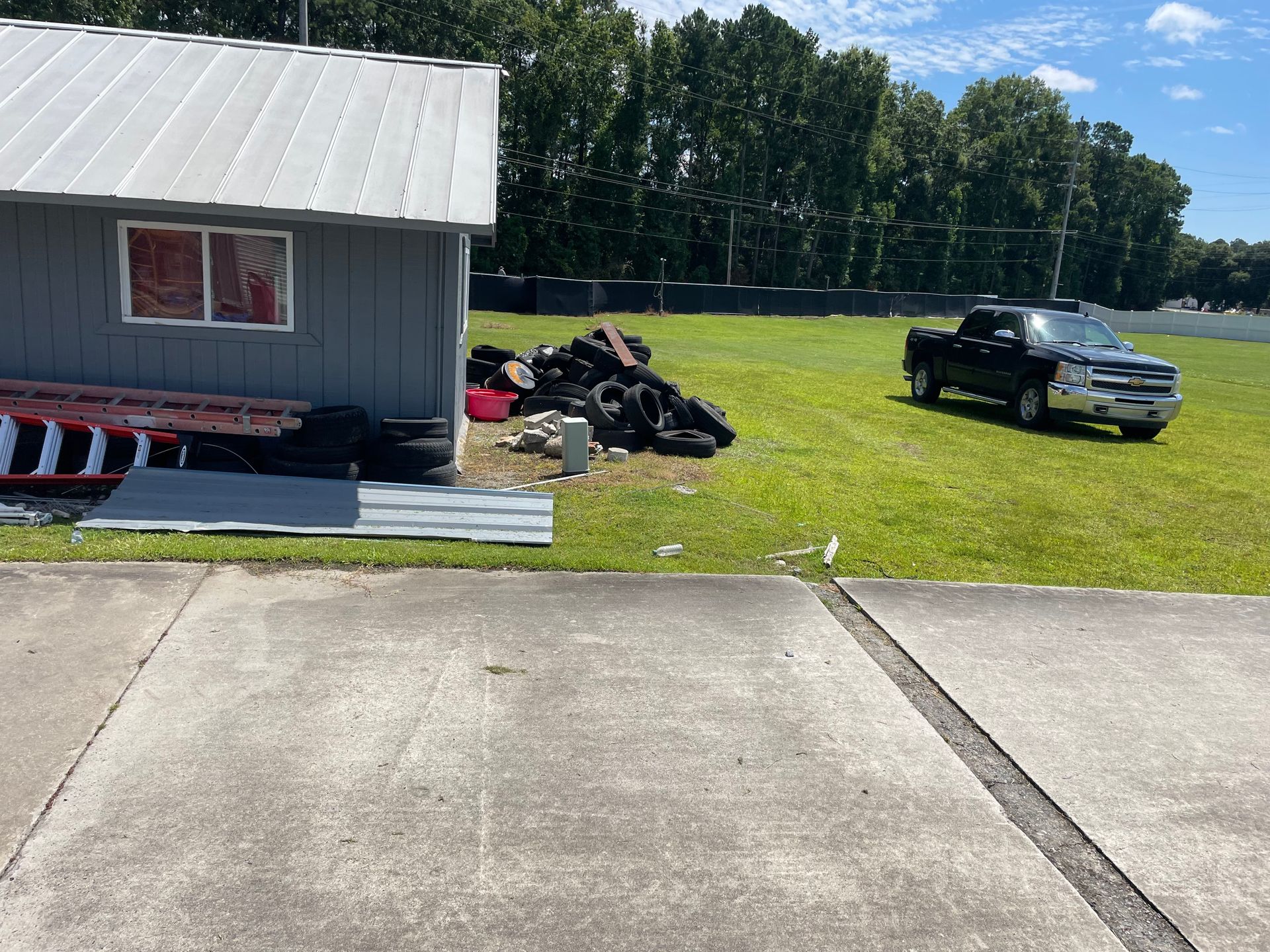 A truck is parked in front of a shed in a grassy field.