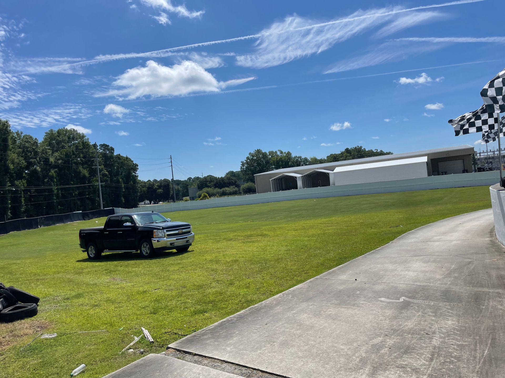 A black truck is parked in a grassy field next to a checkered flag.