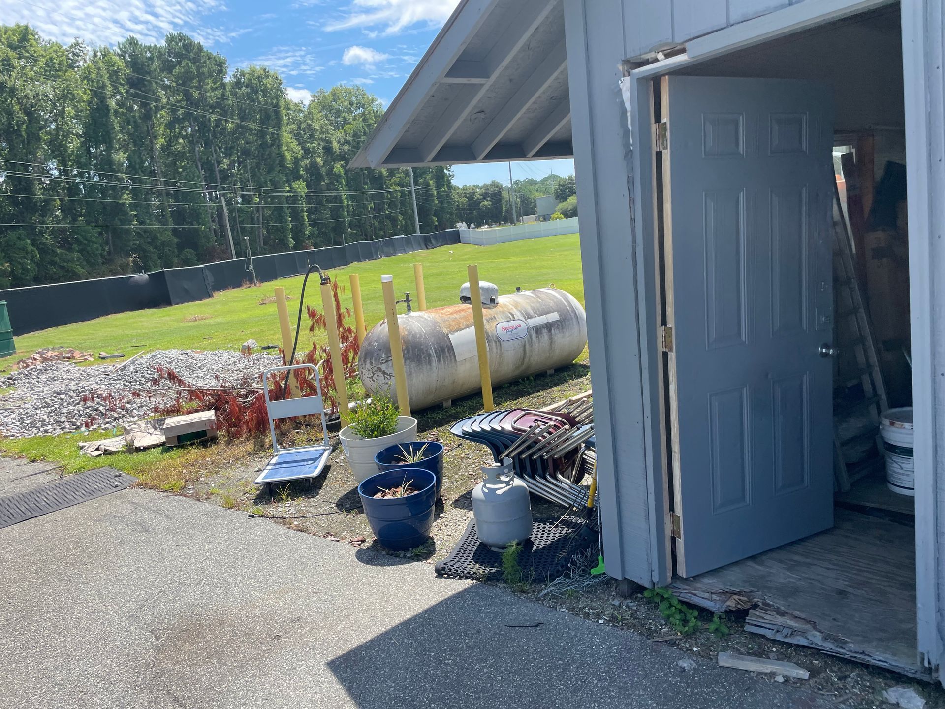 A propane tank is sitting in front of a garage door.