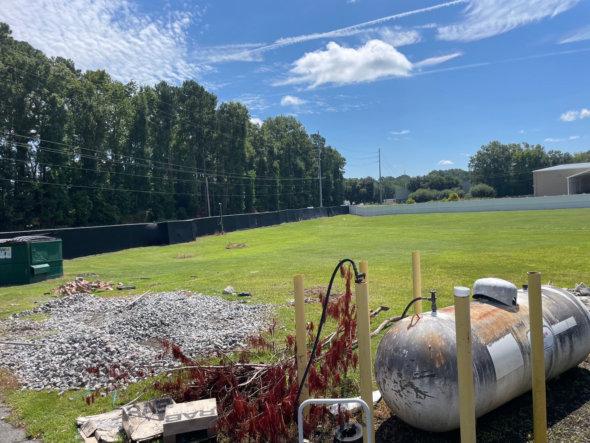 A large propane tank is sitting in the middle of a grassy field.