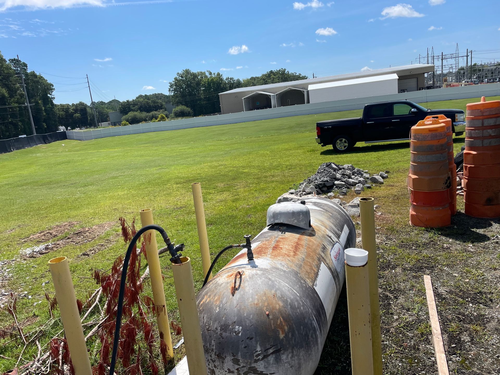 A black truck is parked in a grassy field next to a propane tank