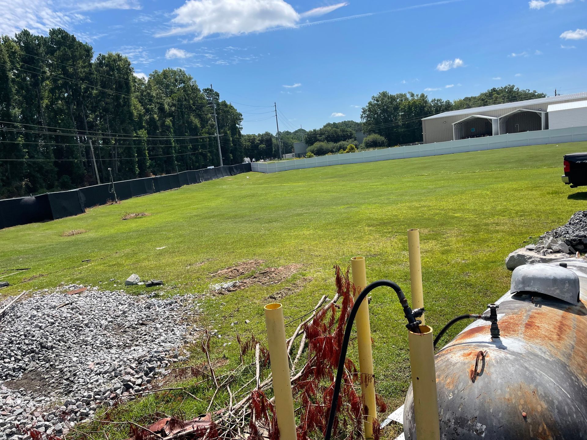 A propane tank is sitting in the middle of a grassy field.