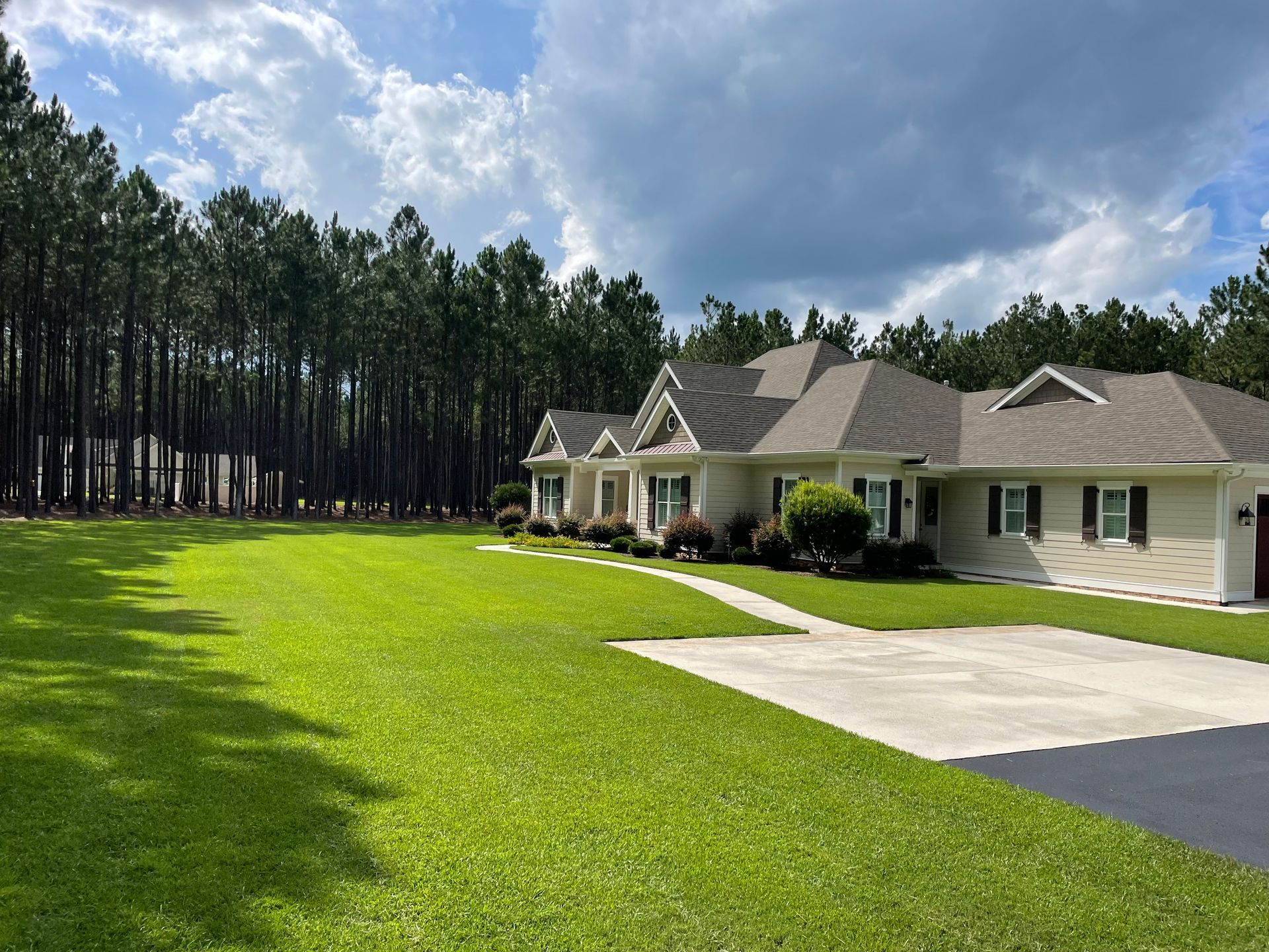 A large house with a lush green lawn in front of a forest.