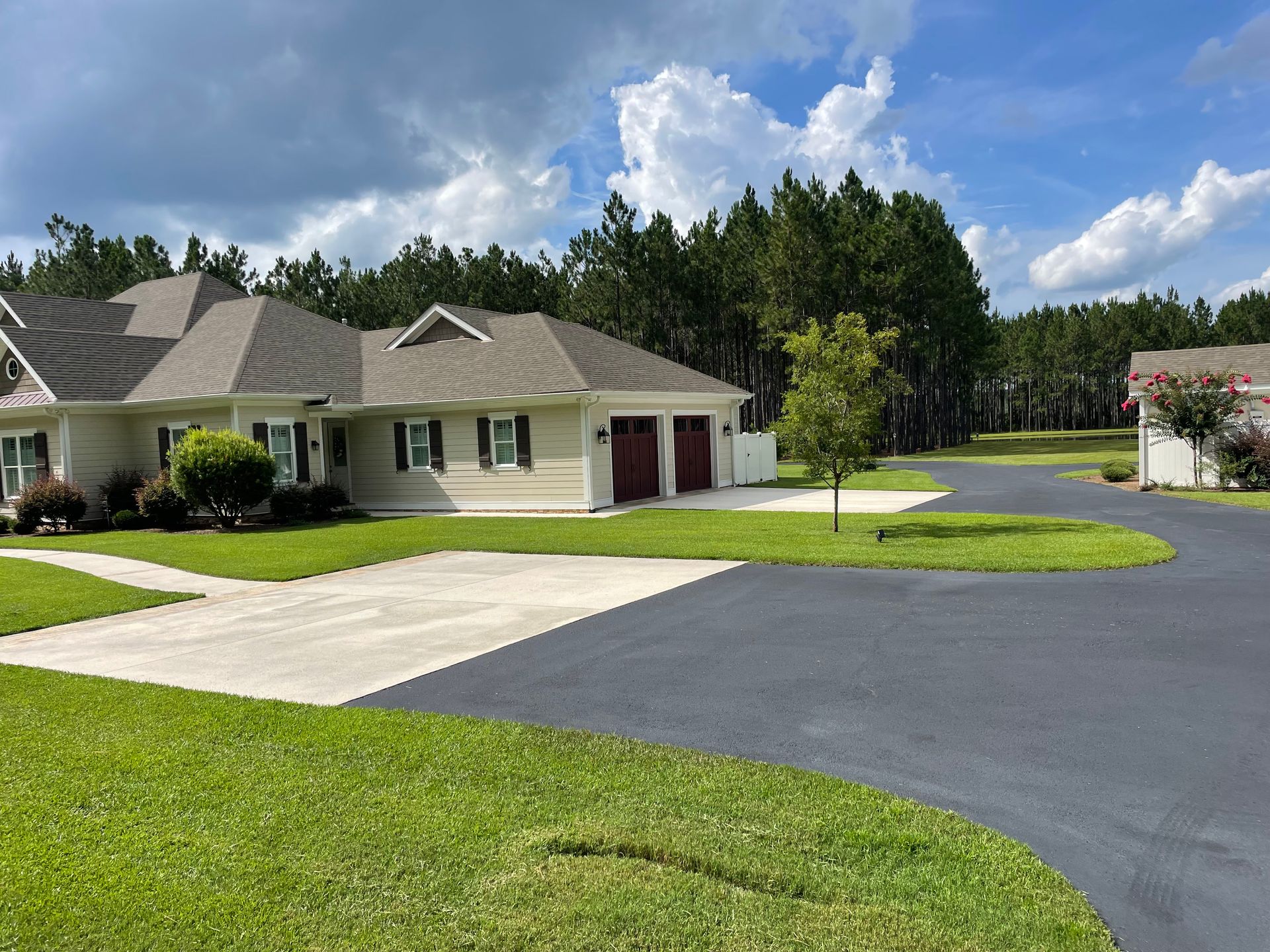 A large white house with a driveway in front of it surrounded by trees.