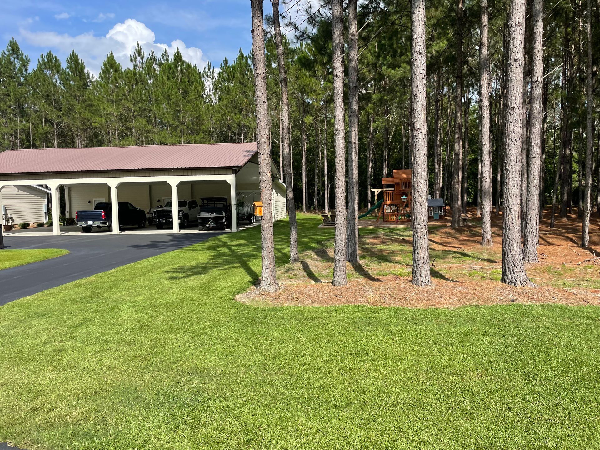 A house with a carport in the middle of a forest.