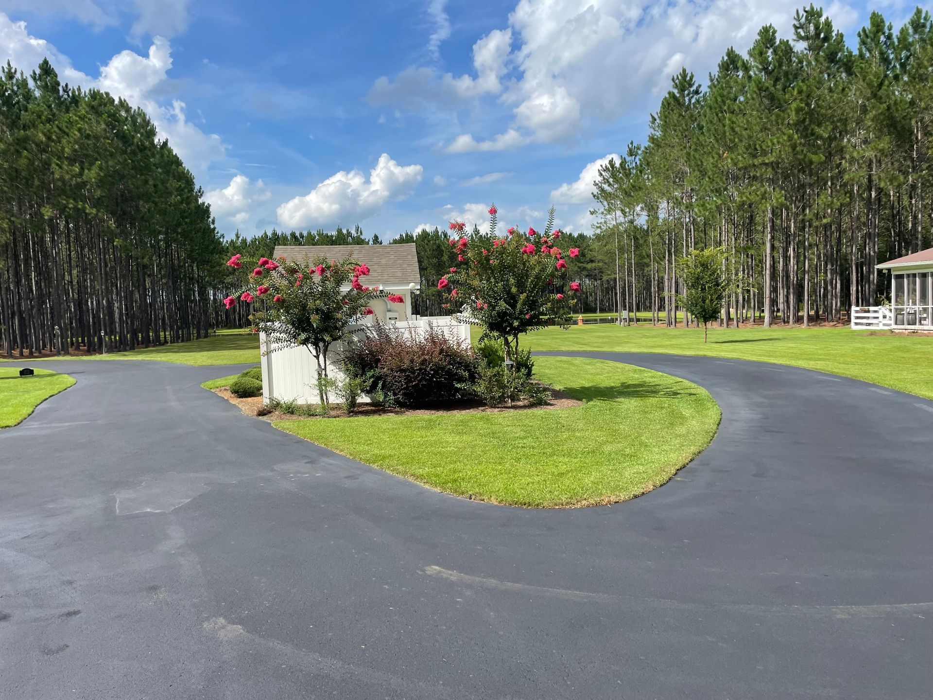 A driveway leading to a house surrounded by trees and grass.