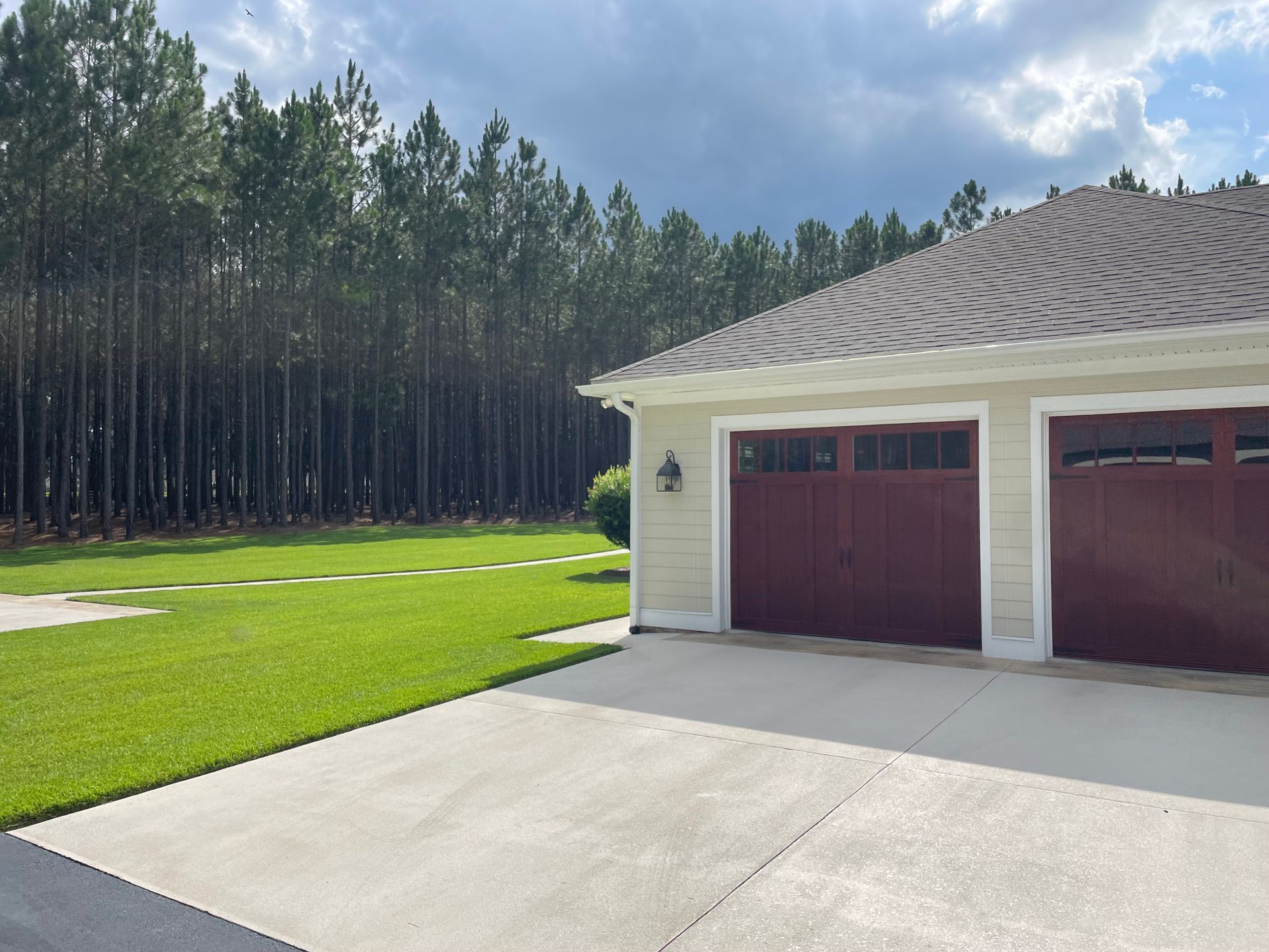 A house with two red garage doors in front of a forest