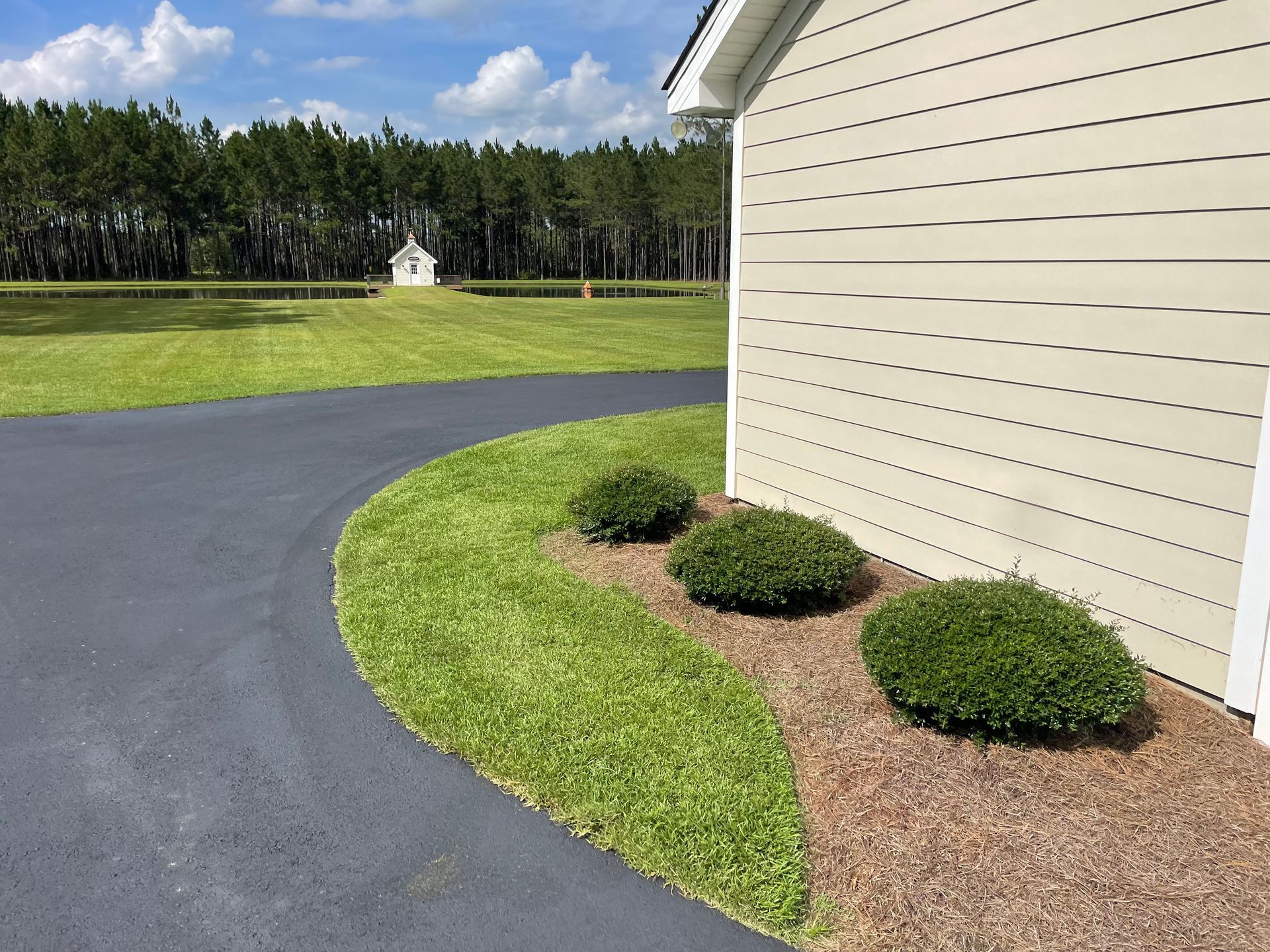 A driveway leading to a house with a shed in the background.